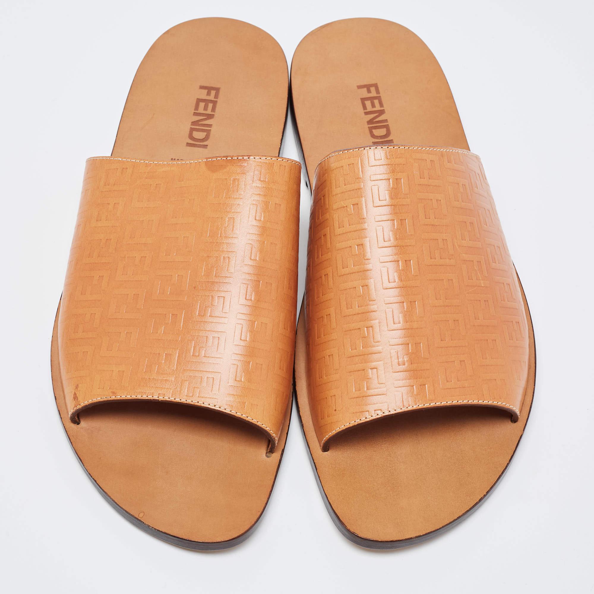 The Fendi slides are luxurious footwear featuring Fendi's iconic Zucca logo pattern embossed on premium tan leather. These comfortable slides offer a stylish and sophisticated design with a branded strap, making them a chic choice for both casual