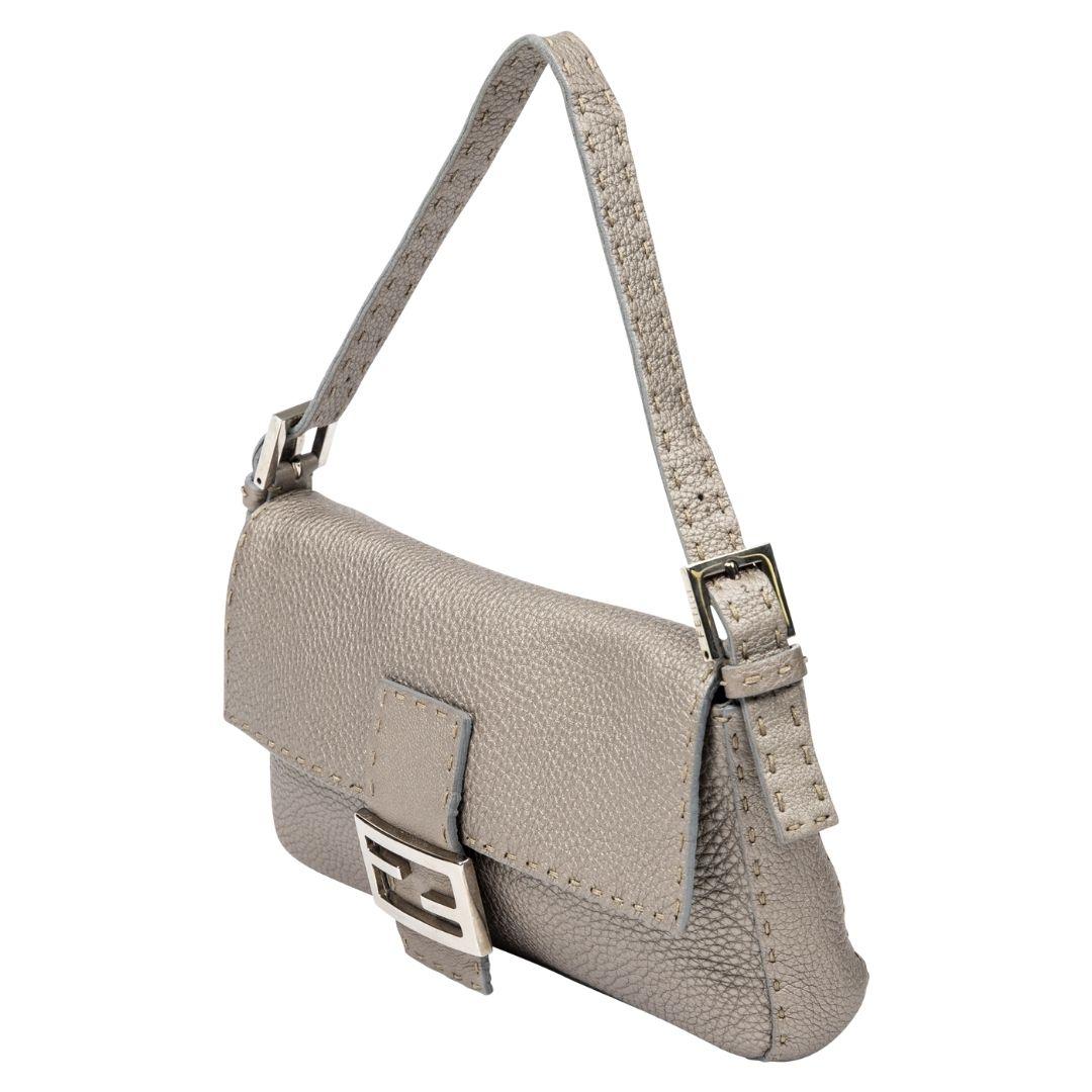 This Fendi Baguette, in sophisticated taupe Selleria leather, is a blend of classic and rare. Accented with silver-tone hardware and a magnetic snap closure, it reveals a suede interior with a secure zippered pocket.

SPECIFICS
Length: 10