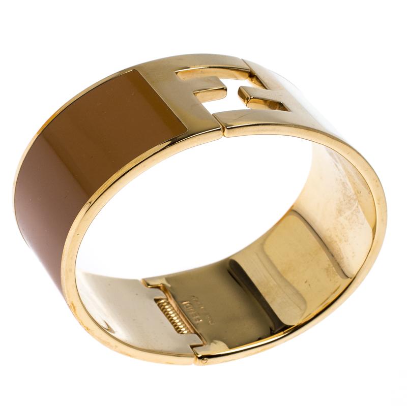 This The Fendista from Fendi is a stylish cuff bracelet crafted to perfection in Italy. The hinged cuff design connects to complete the Fendi logo. The gold-tone hardware complements the brown and cream enamel panels.

Includes
Original Box
