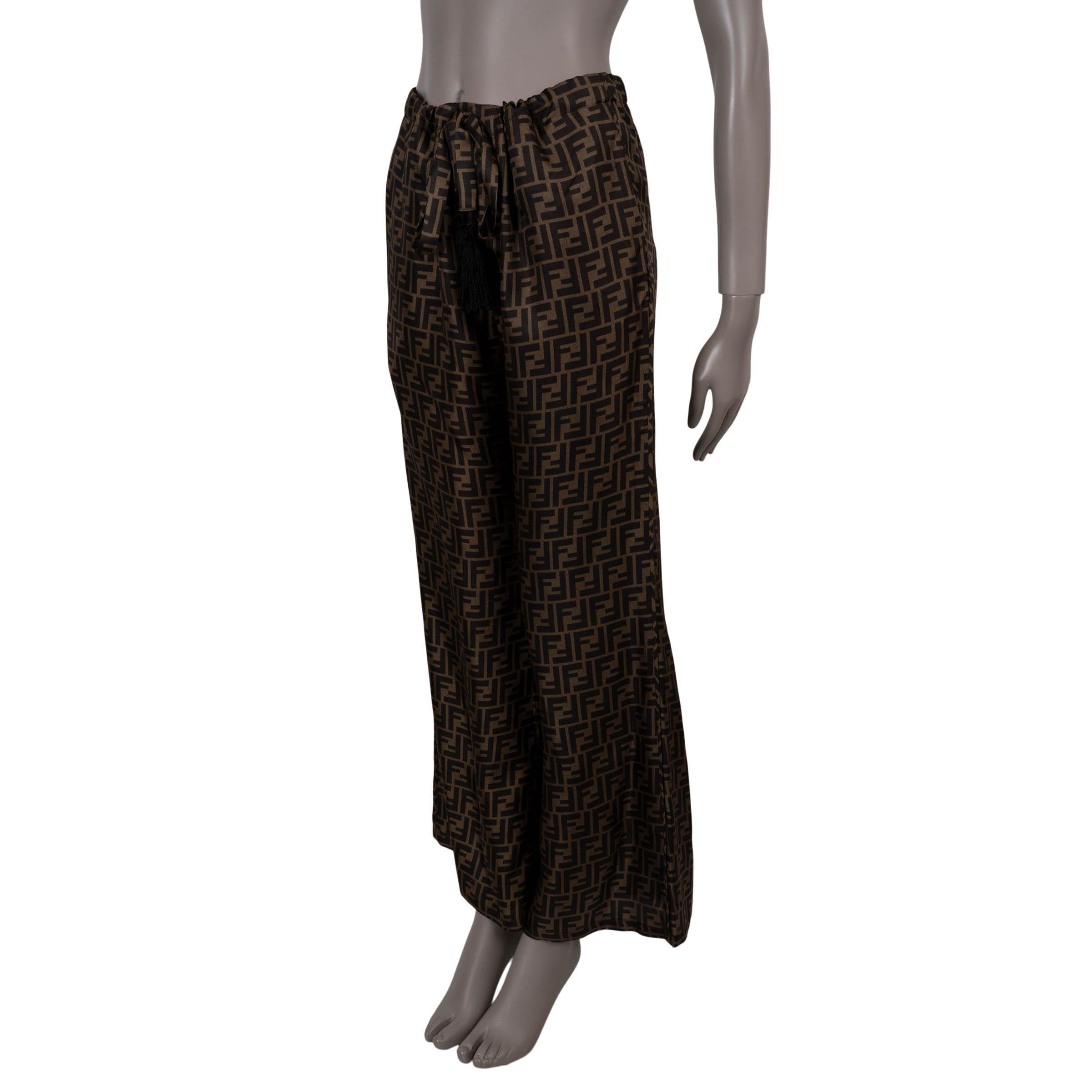 Ce pantalon palazzo 100 % authentique de Fendi est confectionné en soie Zucca (100 %) de couleurs Fango et Tabac et arbore le monogramme emblématique de la Maison. Conçues avec une silhouette évasée et des jambes larges, elles présentent des poches