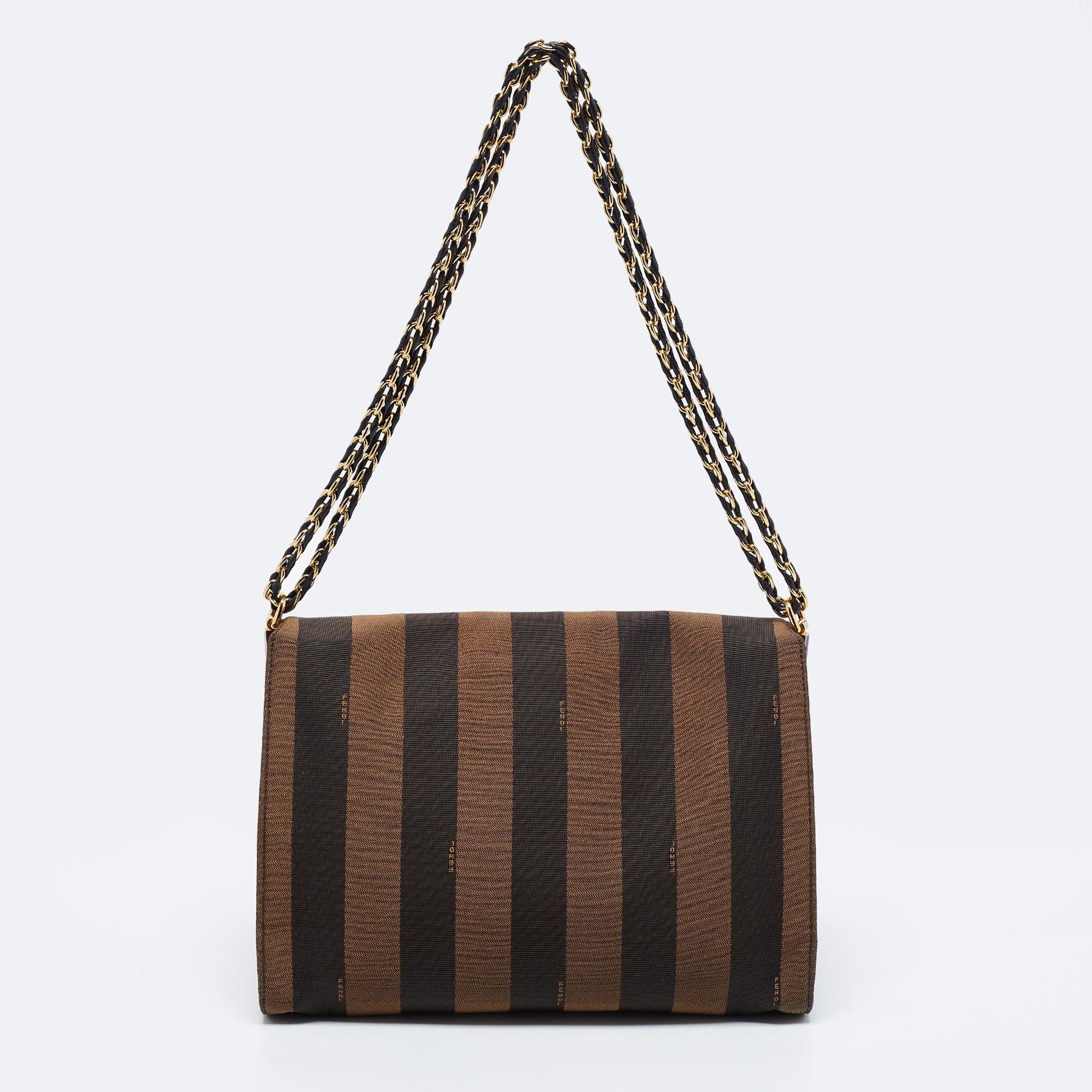 This Claudia bag by Fendi has an eye-catching display and a sophisticated look. Crafted from Pequin canvas, it is held by dual chain handles and gets a recognizable accent with the branded lock closure on the front. The canvas and suede interior of