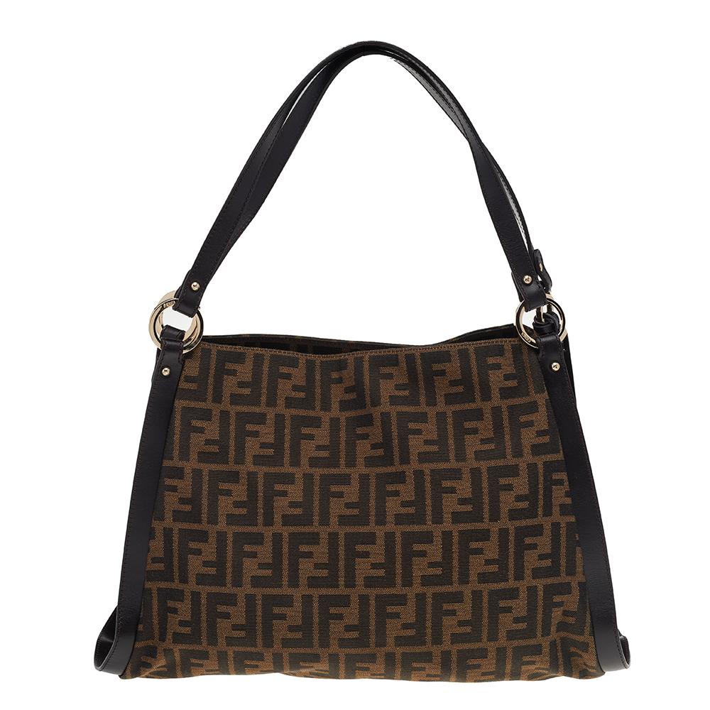 Give your wardrobe an instant signature touch with this graceful Zucca canvas and leather handbag. The inside of this chic bag is beautifully lined with fabric for perfection. This Fendi tote is complete with dual top handles and a logo charm to the