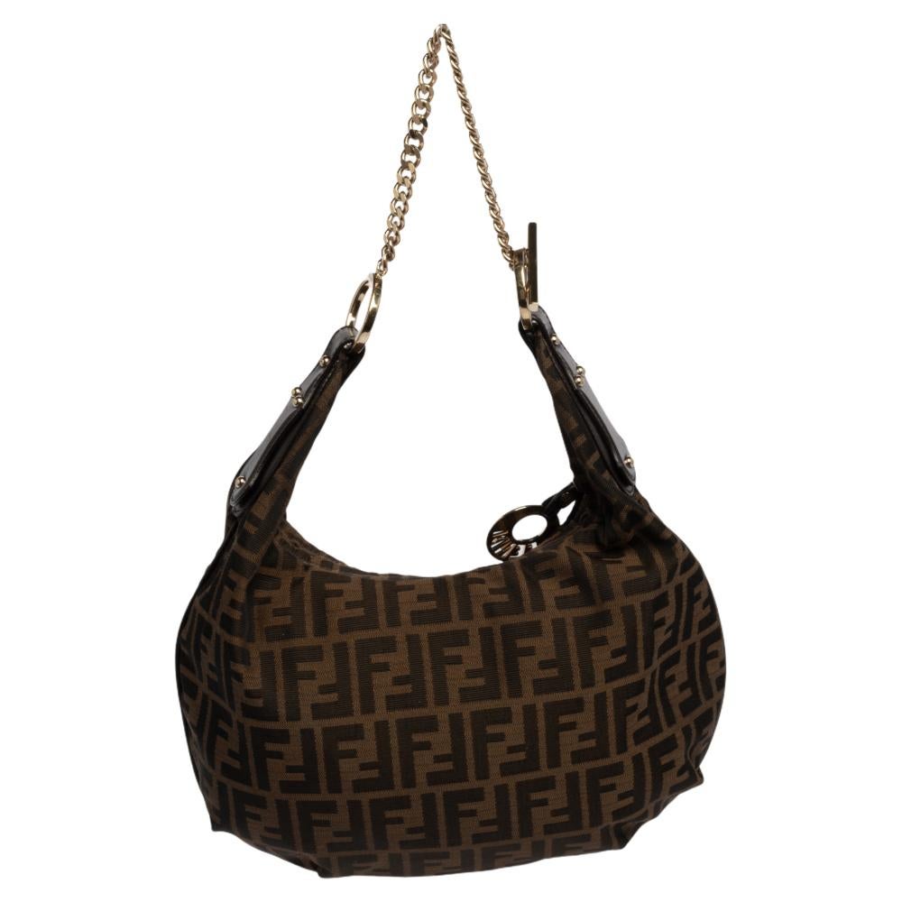 This chic and feminine hobo is from Fendi. The bag is made from classic tobacco Zucca canvas. Gorgeous in appeal, the hobo is easy to carry around. The bag features a chain strap and a top zip closure that opens to a canvas-lined interior which will