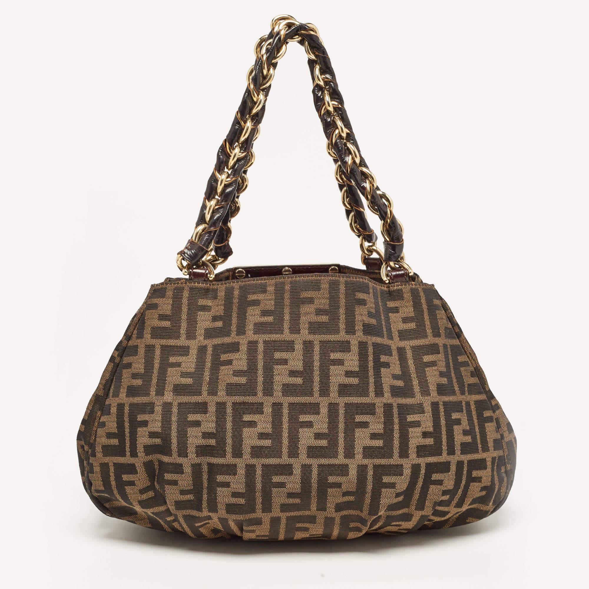 The Fendi Mia shoulder bag exudes timeless elegance with its iconic monogram pattern and rich tobacco hue. Crafted from premium canvas, it features a chic shoulder strap for effortless carrying, making it the epitome of sophistication and