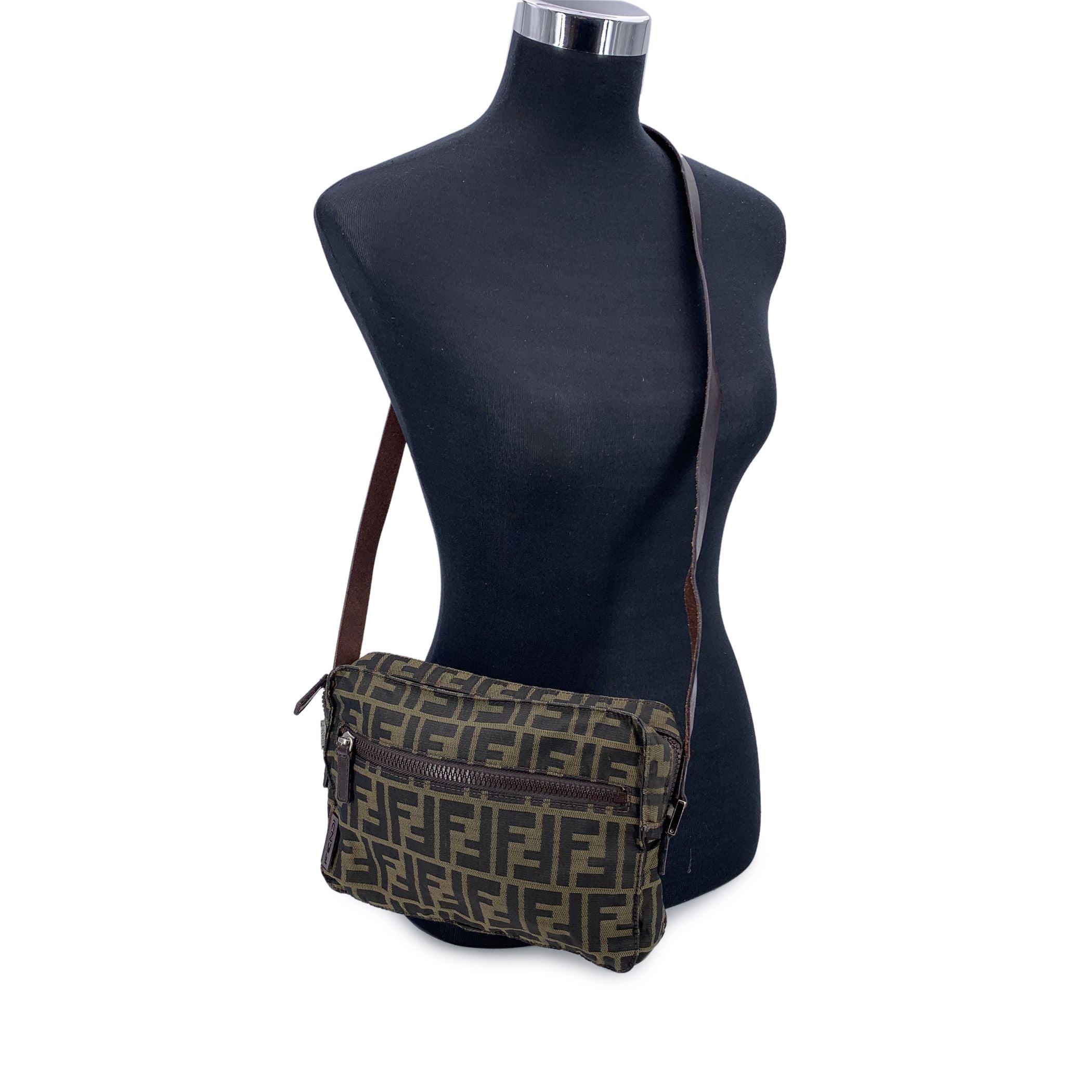 Step into the world of timeless style with the Fendi Messenger Bag, a versatile piece that perfectly balances luxury with practicality. Crafted from the iconic black and tobacco Monogram Zucca canvas, this bag features the distinctive Fendi logo