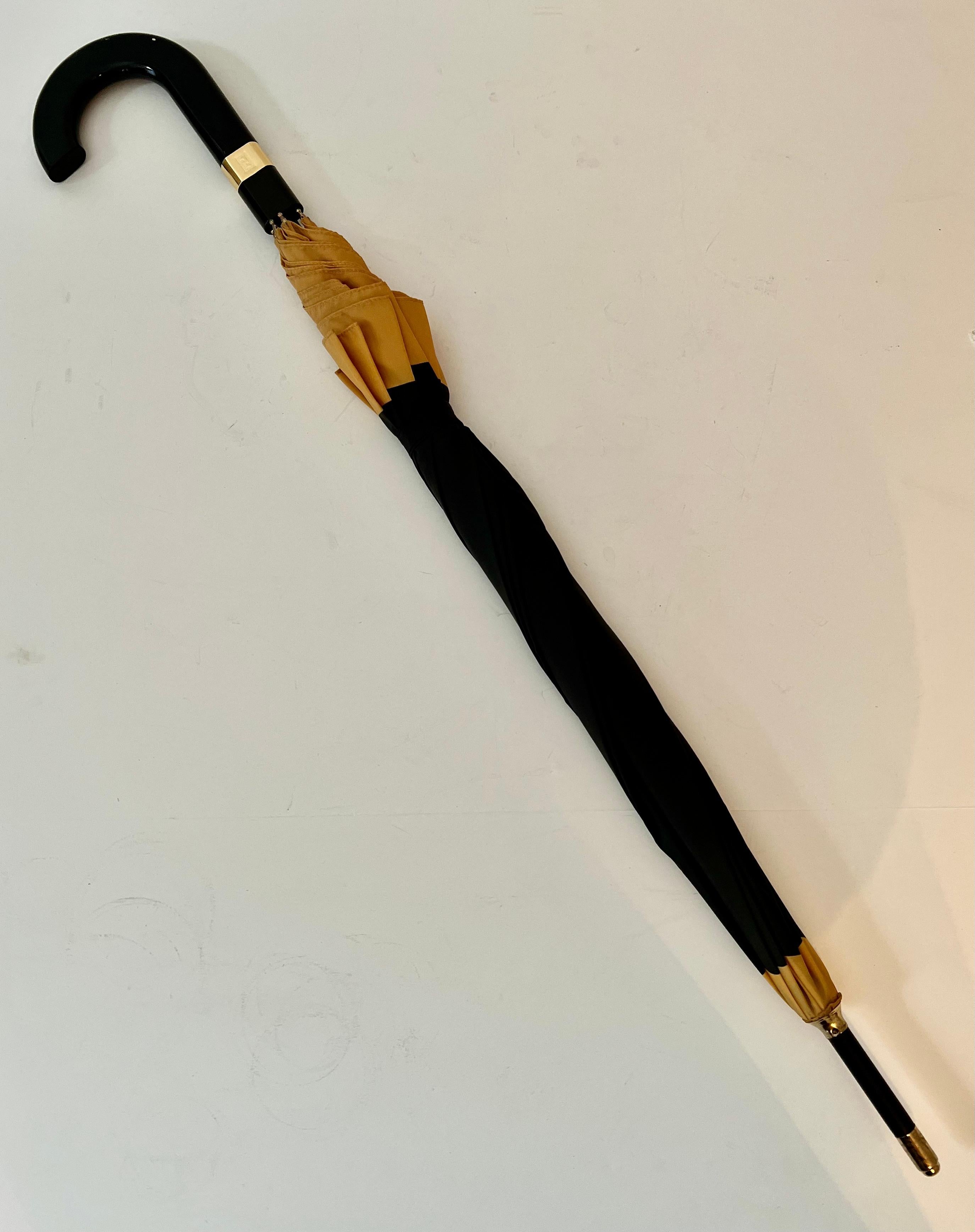 A wonderful black and gold umbrella by Fendi - signed Fendi Perfumes. In wonderful condition, design works well unisex - full sized with case - sleek handle flattened and with brass band 