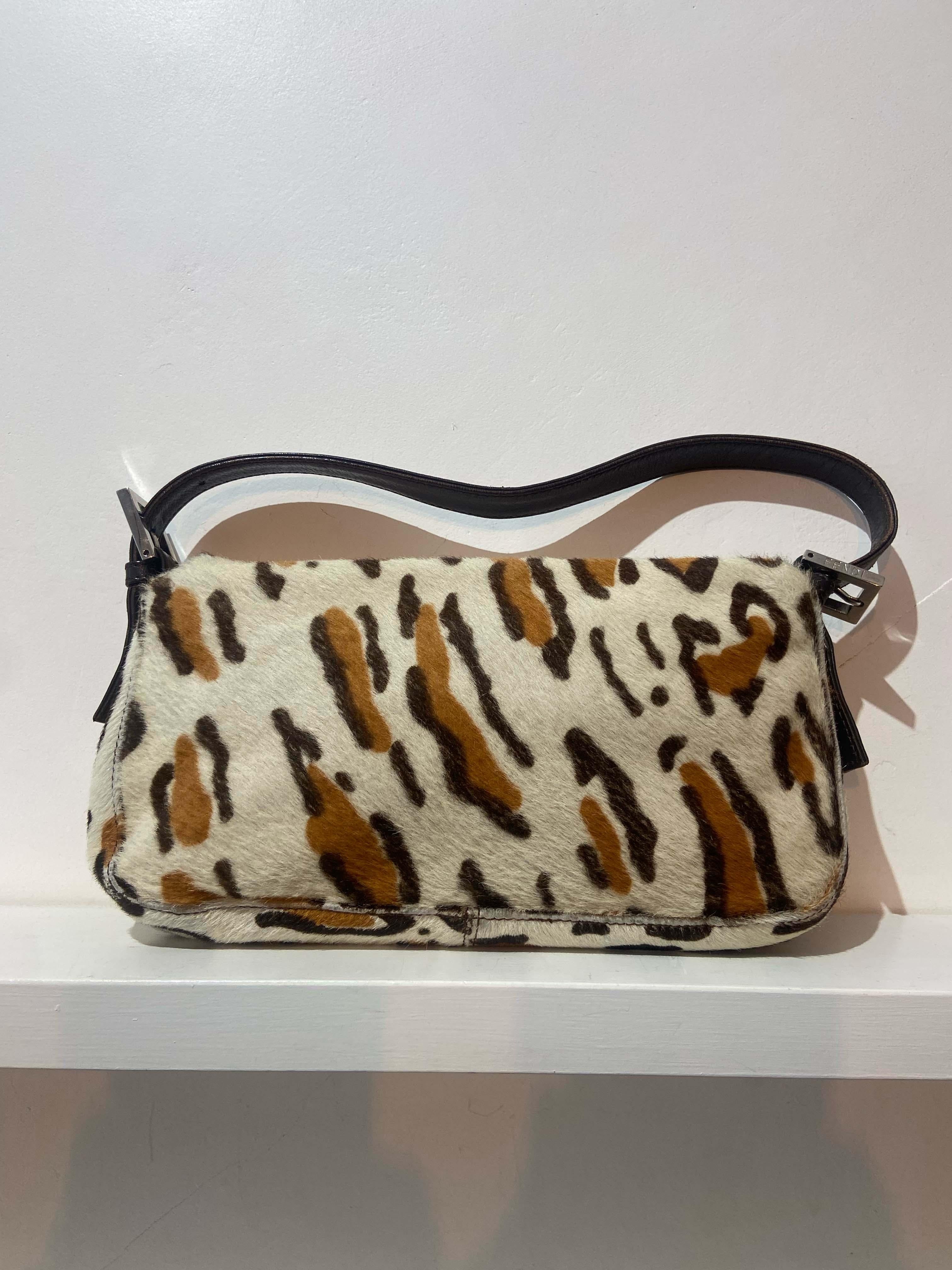 Vintage Fendi late 1990’s calfskin shoulder baguette bag. Features the rare blue and brown cow print allover, adjustable leather strap with Fendi branded hardware buckles, iconic Fendi leather and metal front flap with magnetic closure and inner zip