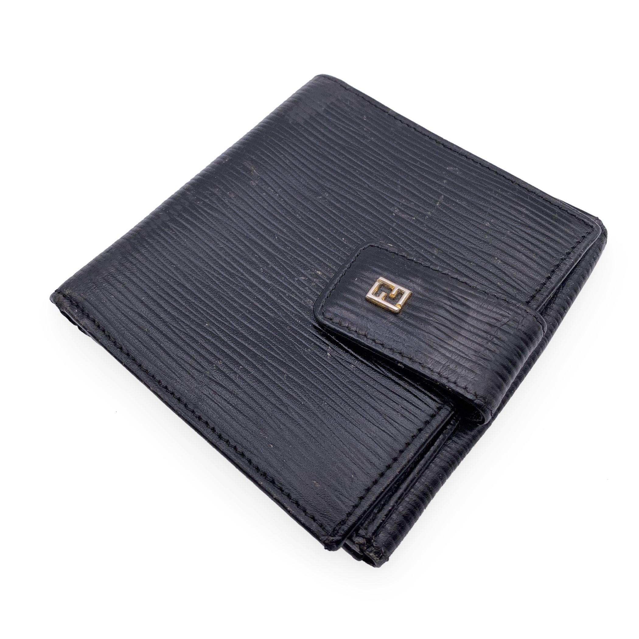 Vintage Fendi wallet in black epi leather. Bifold design. Fold over strap with button closure. 1 bill compartment, 10credit card slots, 2 open pockets and 1 coin section with kiss-lock closure. FF logo on the front. Leather and fabric lined. 'Fendi