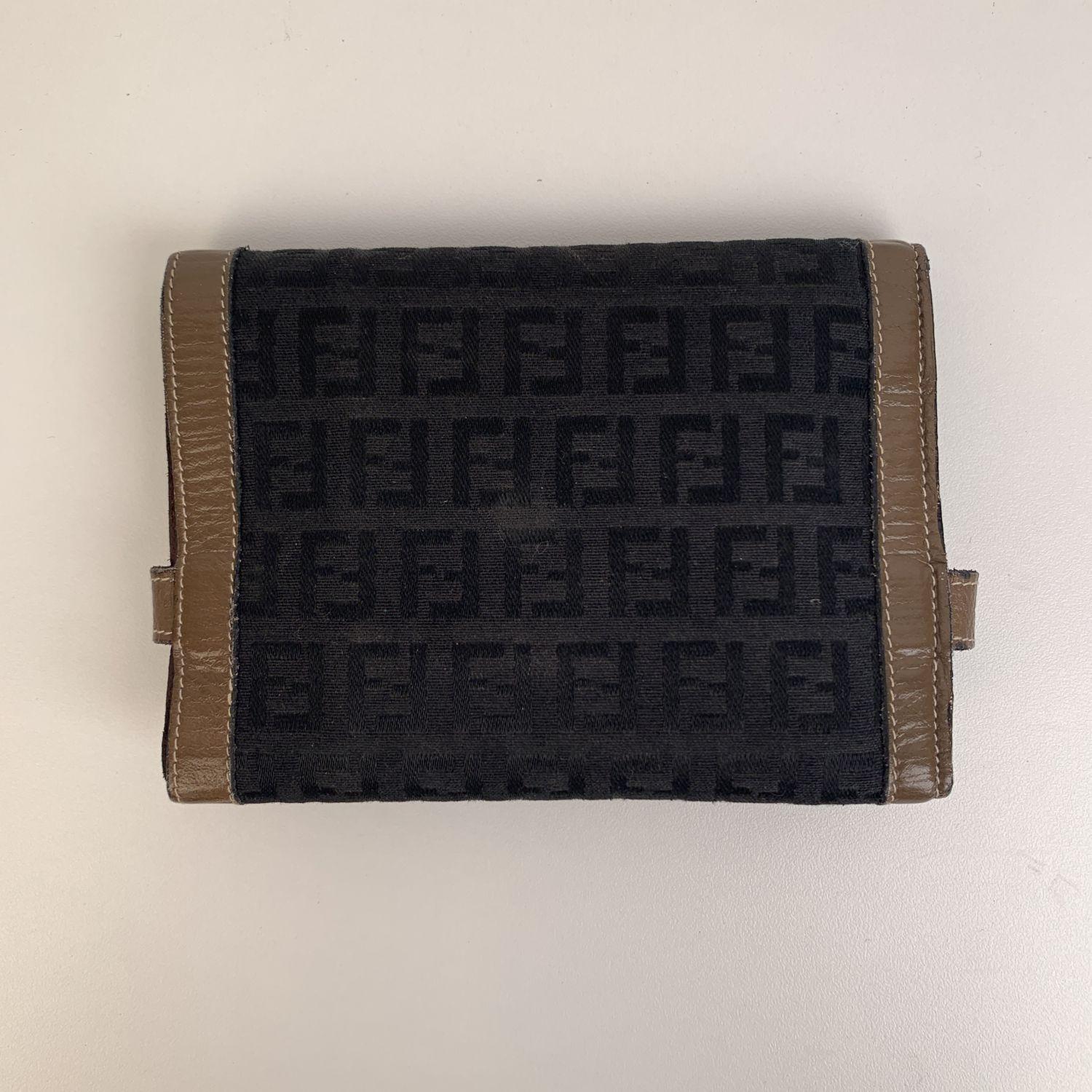 FENDI vintage canvas and leather wallet with FF - FENDI monogram pattern. Bicolor design. Strap Closure and Button Closure. Internal sections: 1 Bill Compartment, 2 Credit Card Slots, 2 Compartment and 1 Coin Purse. Logos / Tags: FENDI Monograms