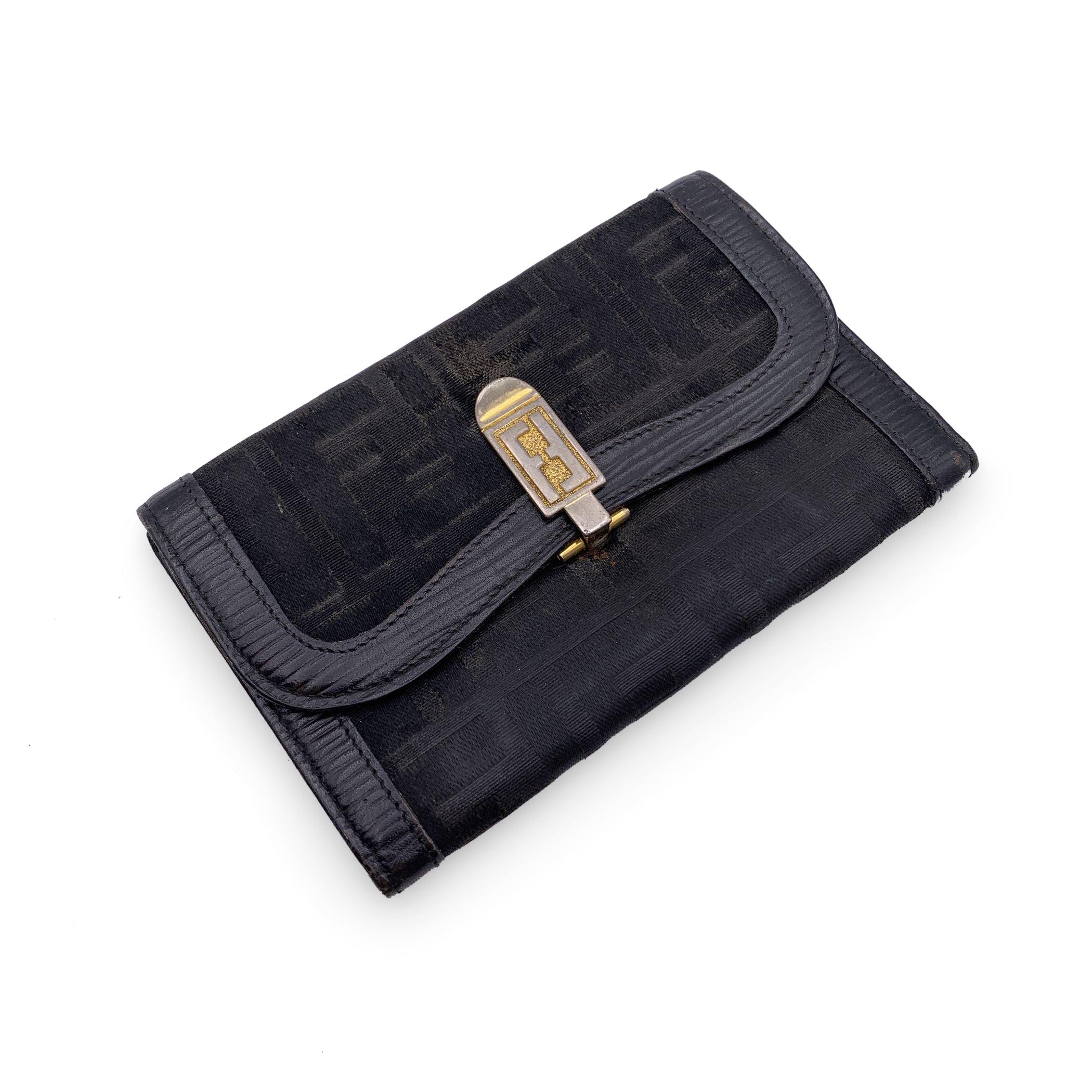 Vintage Fendi wallet in black monogram canvas with leather trim. Flap with clasp closure. 3 open pockets and 1 pocket with button closure inside. Clasp closure with FF logo on the front. Leather lining. 'Fendi s.a.s Roma - Made in Italy' embossed