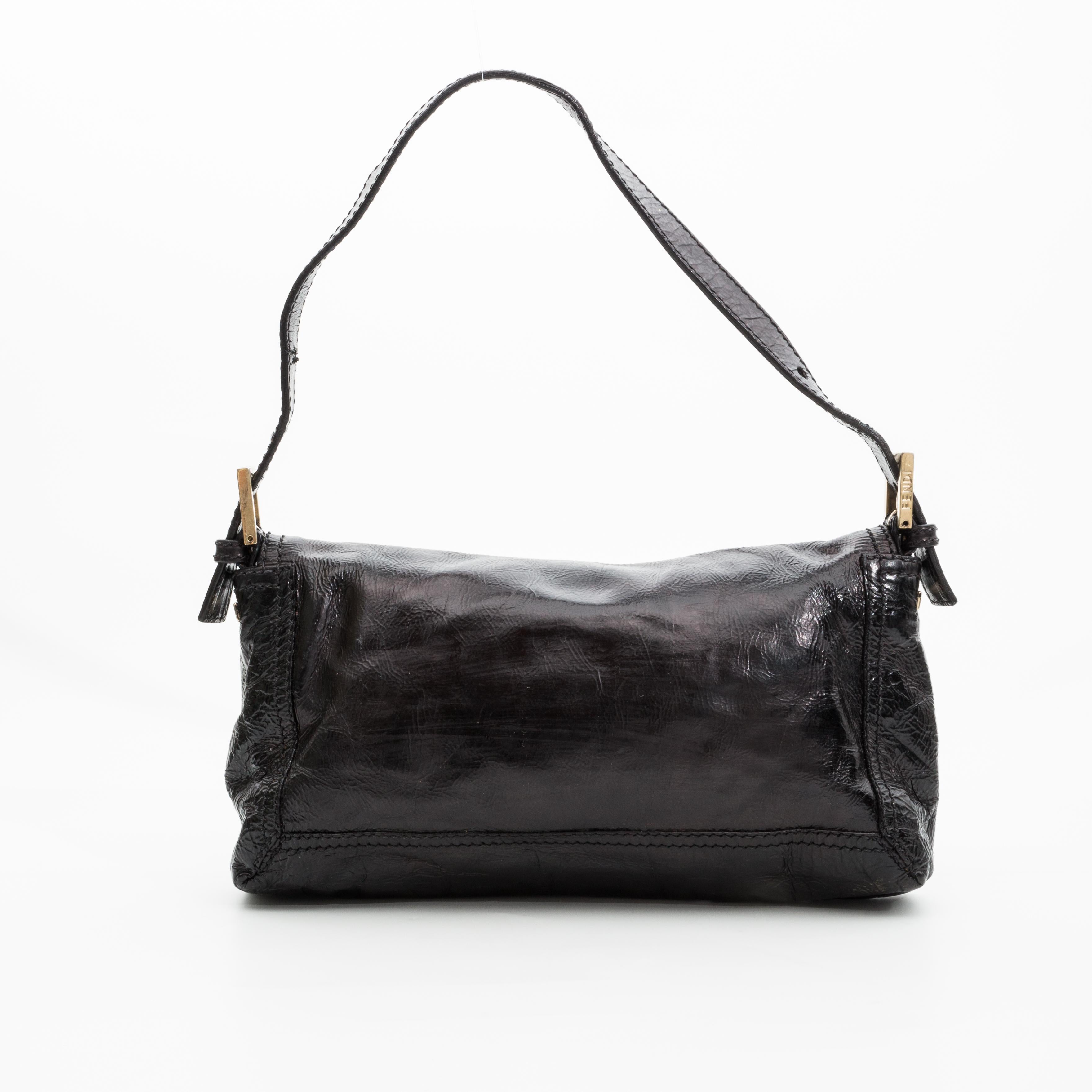 This bag the smaller version of this model.  The bag features textured patent leather, a large Fendi Forever clasp at front flap, snap closure, a removable shoulder strap as this can be worn as a clutch and brown woven fabric interior