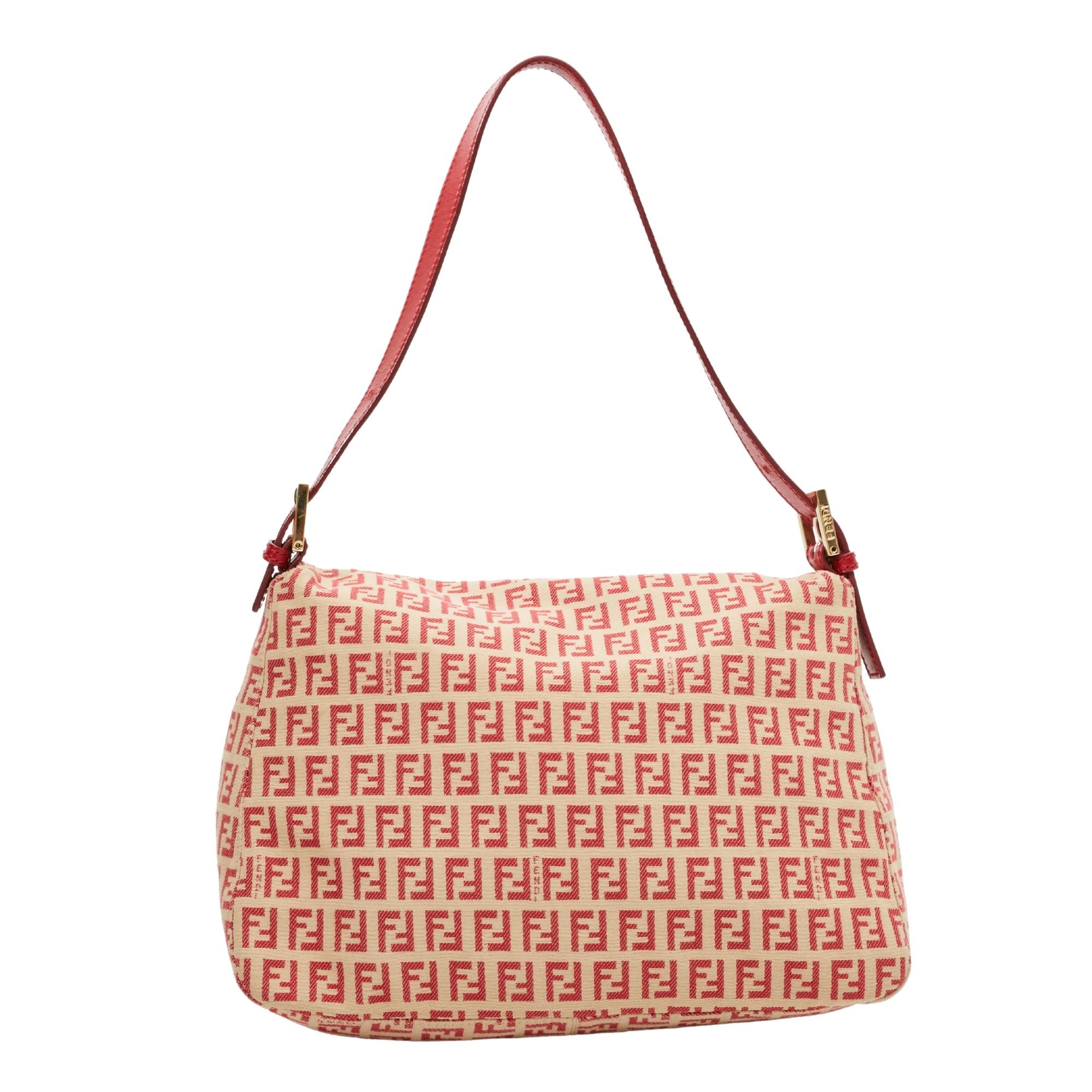 This Mama baguette is made with beige canvas with red Fendi Zuccino embossing throughout. The bag features an adjustable looping leather strap, polished silver buckle links for the top strap and a front leather strap with a polished silver FF logo.