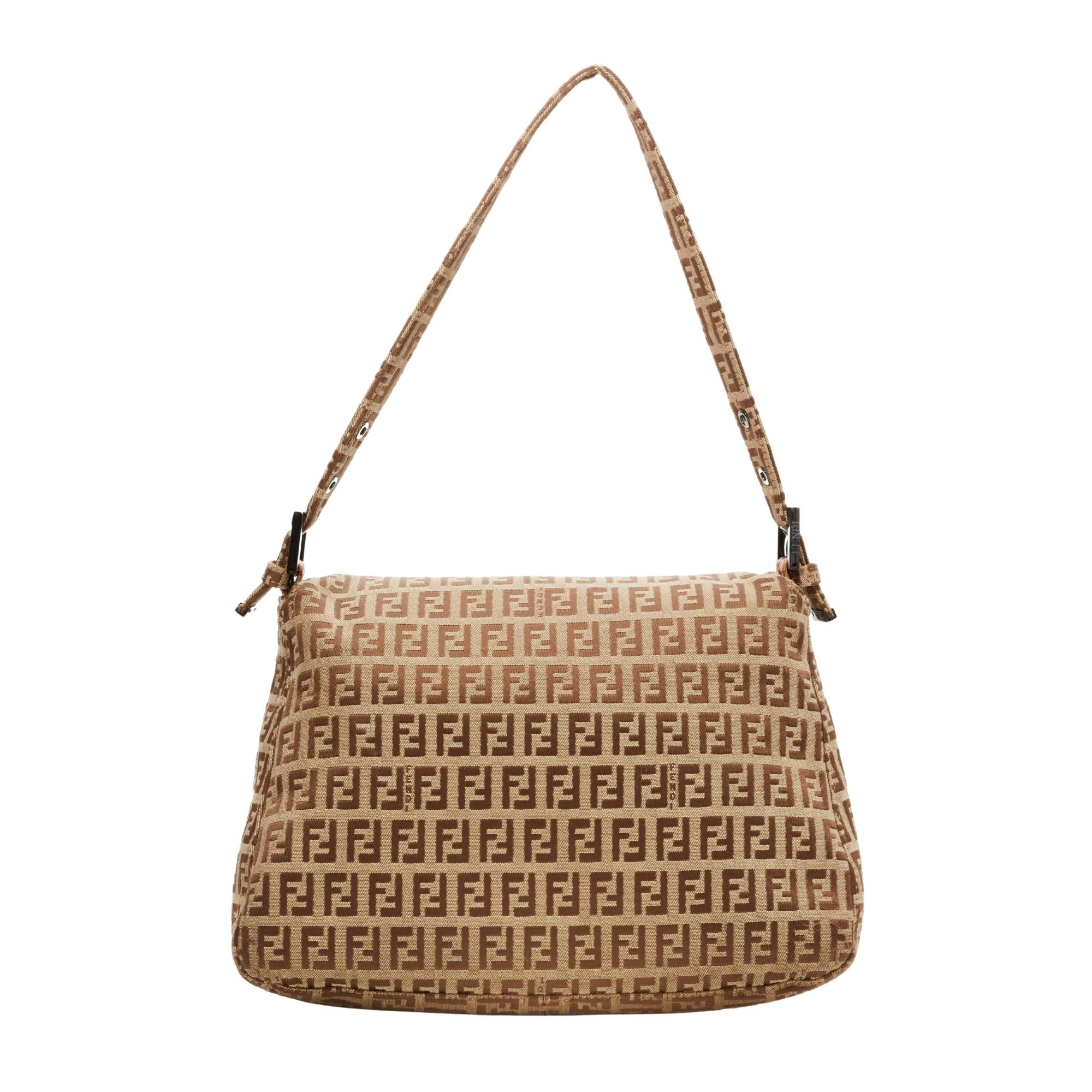 This Mama baguette is made with beige canvas with brown Fendi Zuccino embossing throughout. The bag features an adjustable looping cloth strap, gunmetal silver buckle links for the top strap and a front leather strap with a polished silver FF logo.