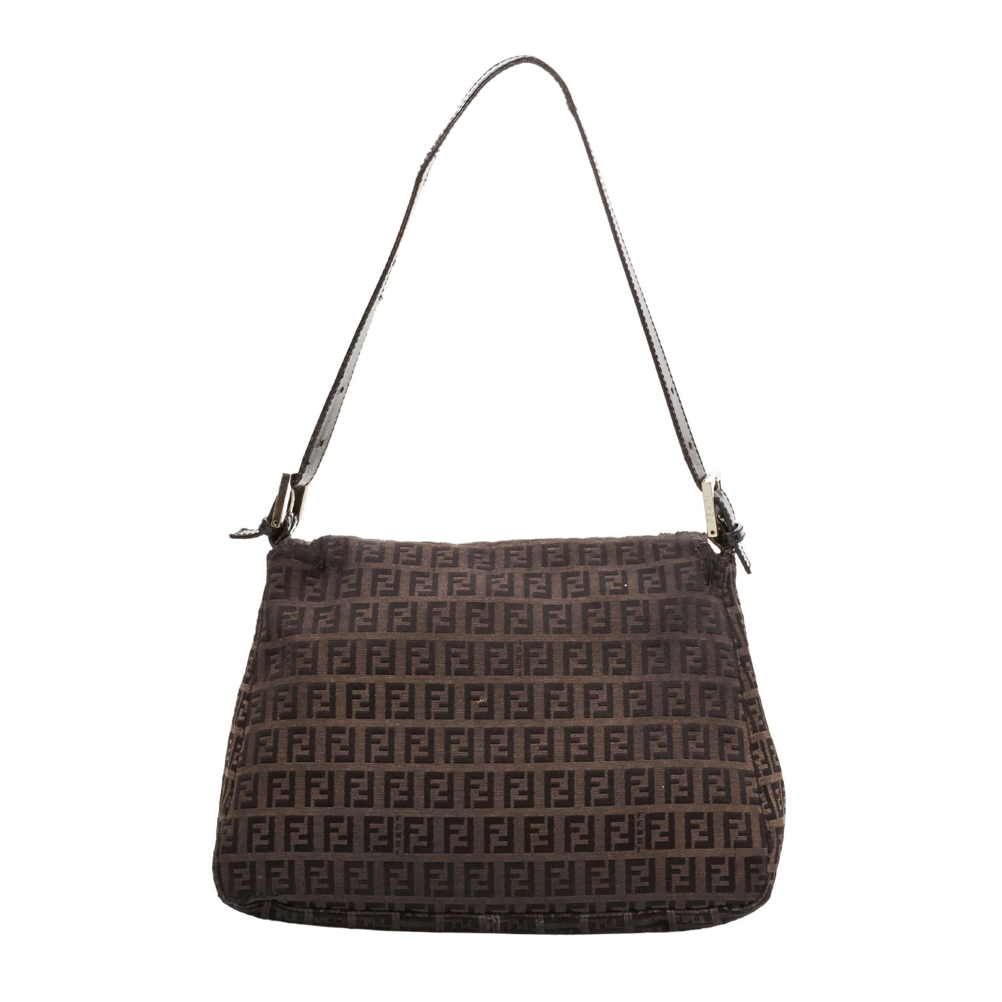 This Mama baguette is made with dark brown canvas with Fendi Zuccino embossing throughout. The bag features an adjustable looping leather strap, sliver buckle links for the top strap and a front leather strap with a sliver FF logo. This flap opens