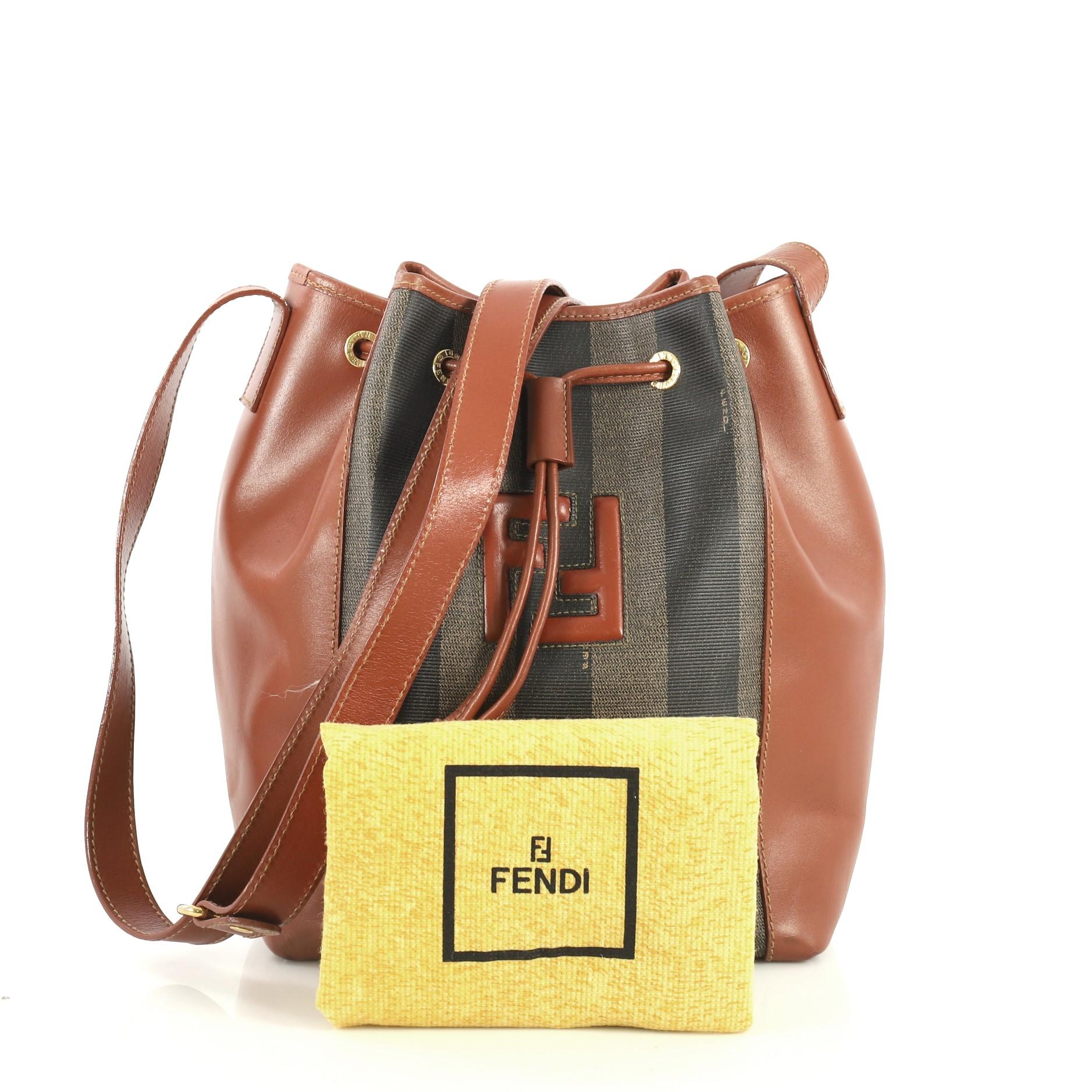 This Fendi Vintage Pequin Bucket Bag Coated Canvas and Leather Small, crafted in Pequin Striped coated canvas and brown leather, features adjustable flat leather shoulder strap and gold-tone hardware. Its drawstring closure opens to a black fabric