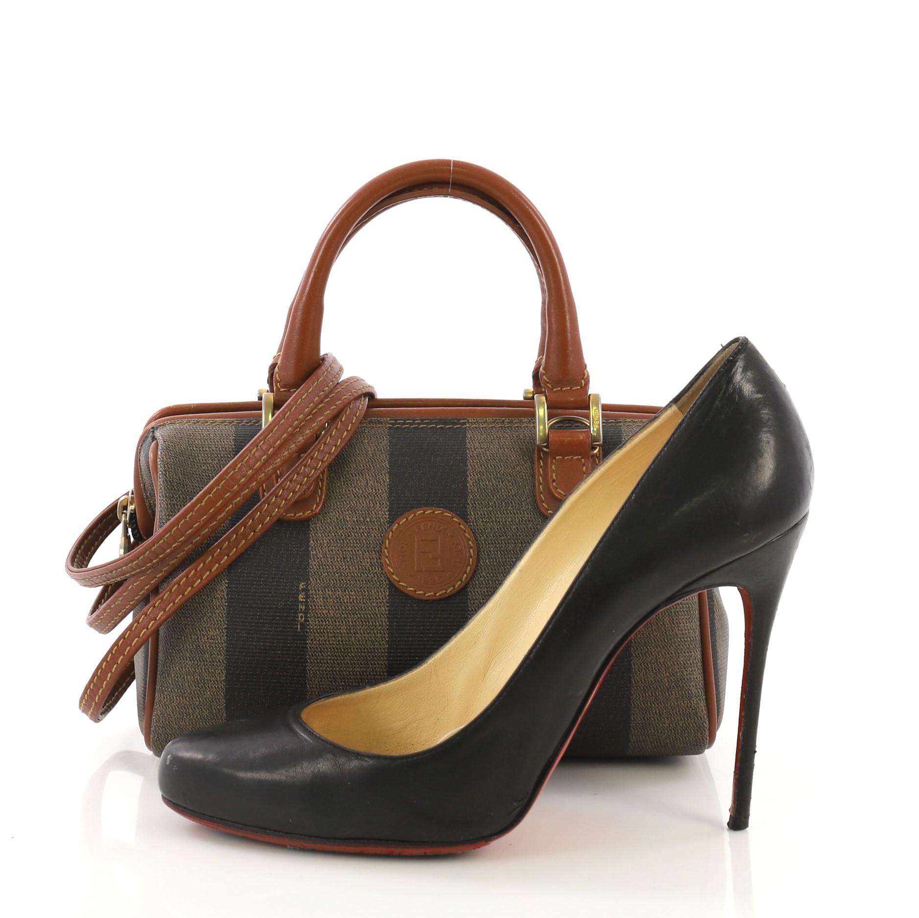 This Fendi Vintage Pequin Convertible Boston Bag Coated Canvas Mini, crafted in brown and black coated canvas, features dual rolled leather handles and gold-tone hardware. Its zip closure opens to a black leather interior. **Note: Shoe photographed