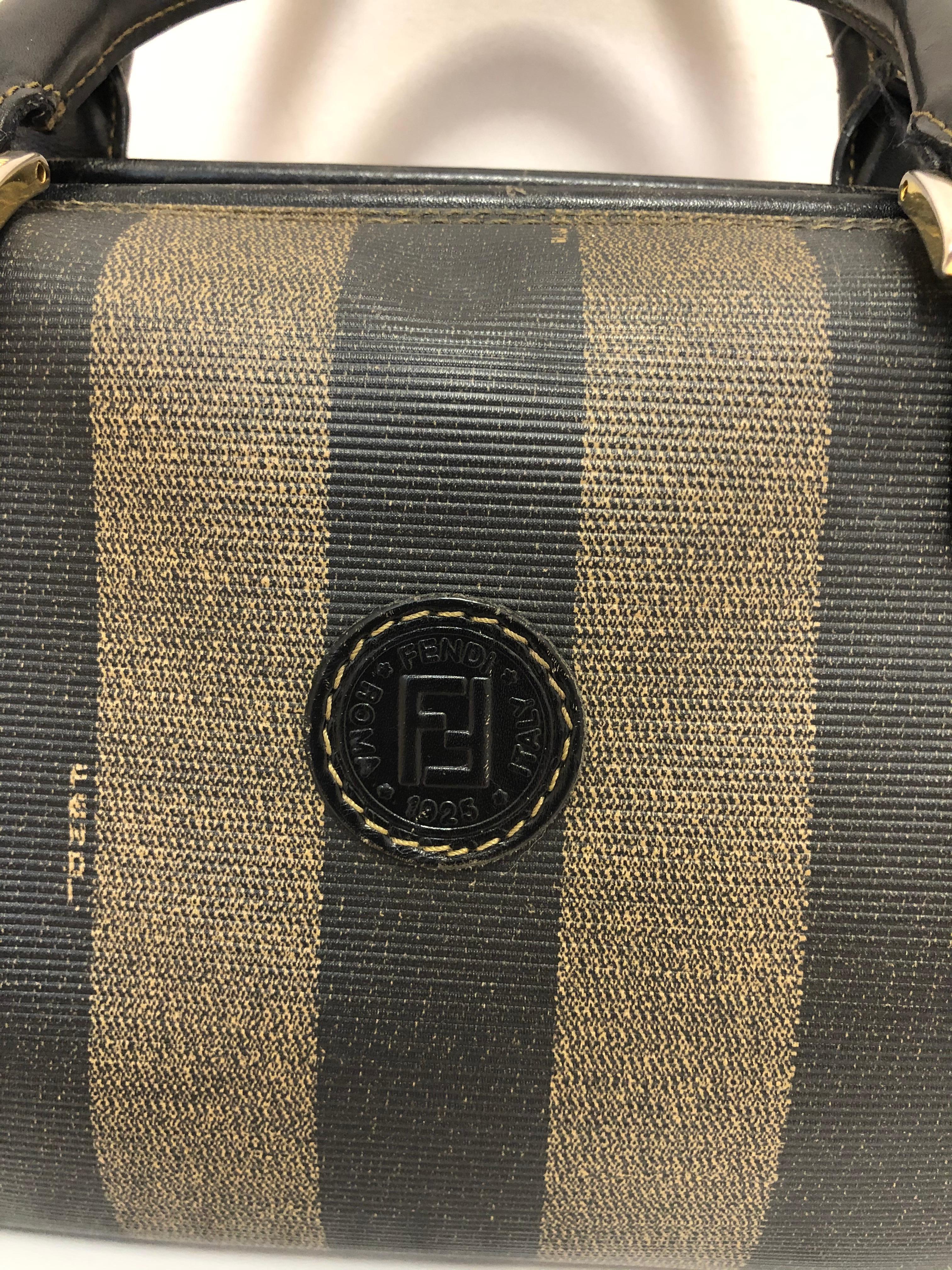 Classic Fendi bag in coated canvas crafted in brown and black, with a black fabric lining. There are two rolled handlesand goldtone hardware. The bag is in very good condition with the exception of two small tears on the lining. I have therefore