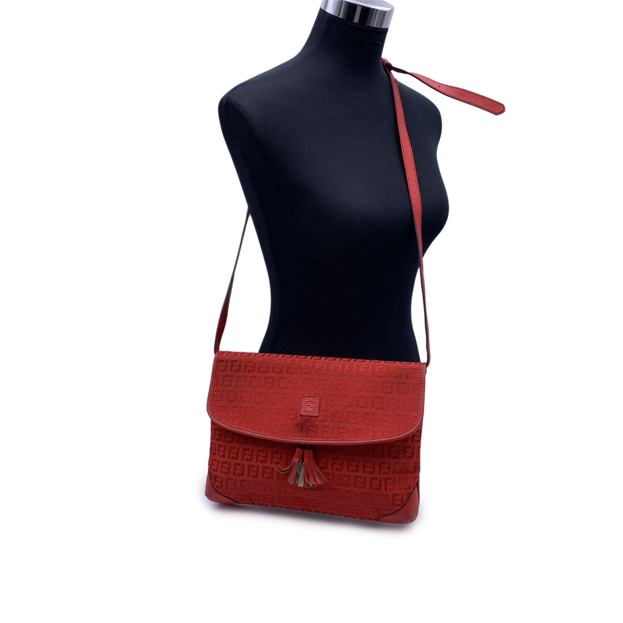Vintage Fendi messenger bag made in FF monogram canvas with genuine leather trim and shoulder strap in red color. Flap with magnetic button closure. 2 tassels on the front. 1 side zip pocket inside. 'FENDI s.a.s Roma - Made in Italy' embossed inside