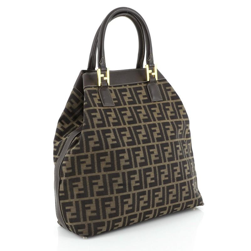 This Fendi Vintage Zip Tote Zucca Canvas Medium, crafted from black and brown zucca canvas, features dual rolled handles, leather trim and gold-tone hardware. It opens to a brown fabric interior. 

Condition: Very good. Creasing on exterior, wear