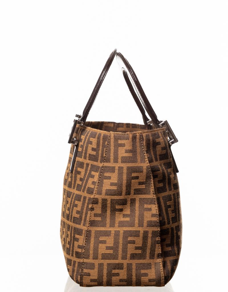Vintage Fendi handbag is made with brown Zucca fabric and features sliver metal logo buckle accents, leather finishes, dual leather top handles, snap closure at top and woven fabric interior lining.

COLOR: Brown
MATERIAL: Fabric
ITEM CODE: