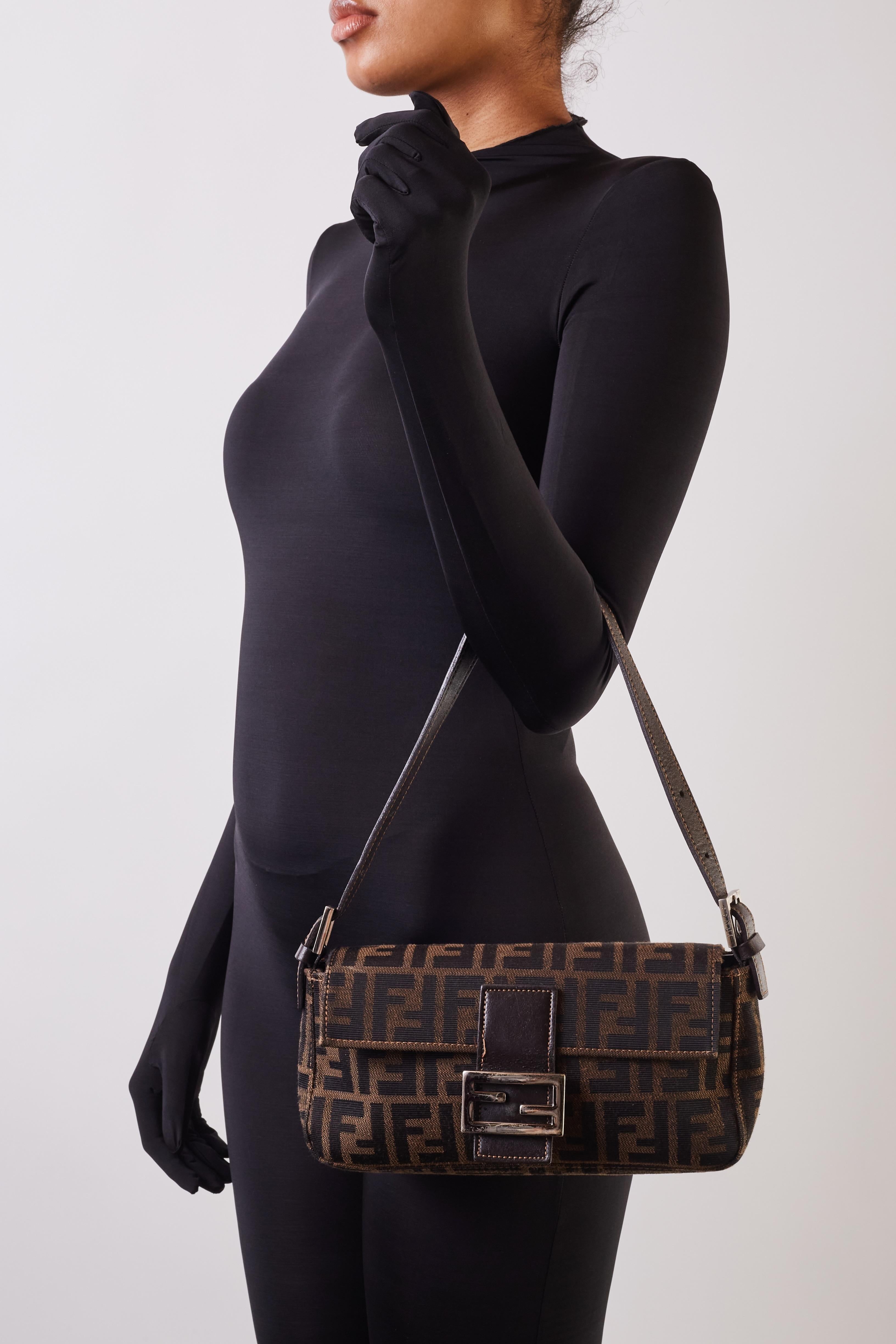 This is an authentic FENDI Zucca Baguette in Tobacco. This stylish baguette is crafted of tobacco-colored Fendi FF on Zucca canvas. The bag features a dark chocolate brown looping leather shoulder strap and trim with a facing flap and polished