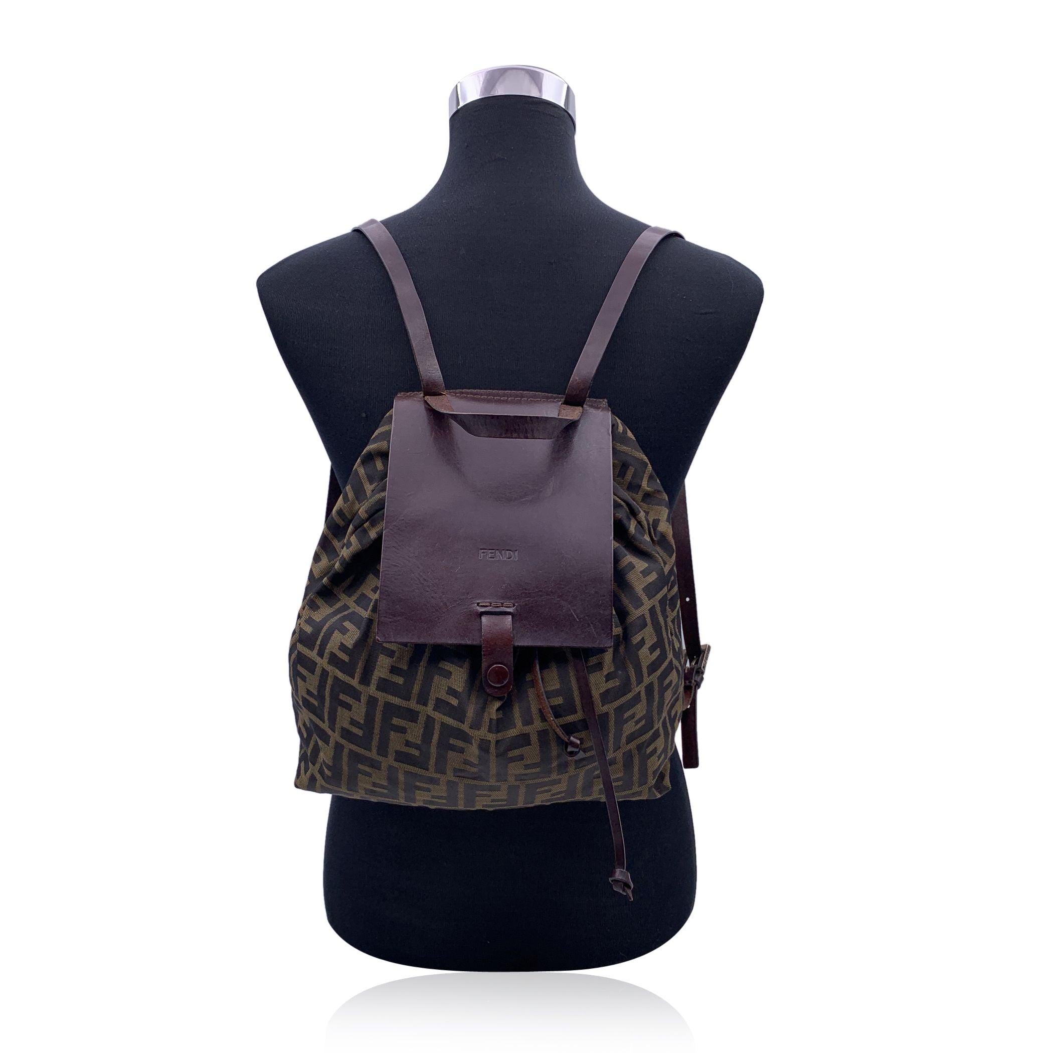 FENDI Zucca Drawstring Backpack bag, crafted of Fendi FF Zucca canvas with dark brown leather flap, drawstring, adjustable shoulder straps and top carry handle. The top flap opens to a matching fabric interior with a side zip pocket. 'Fendi - Made