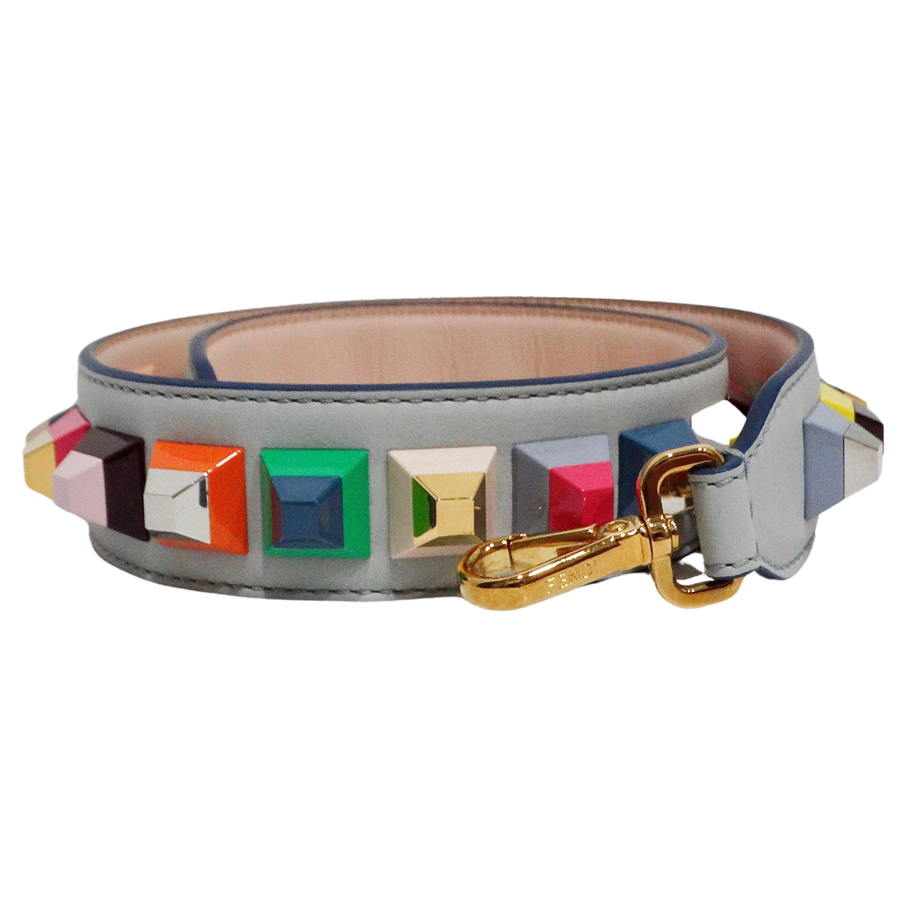 The Fendi Vitello Dolce Studded Bag Strap is a stylish and playful accessory that adds a vibrant touch to any handbag. Made from high-quality grey-toned blue leather, this strap features an array of multicolor studs, providing a fun and unique pop
