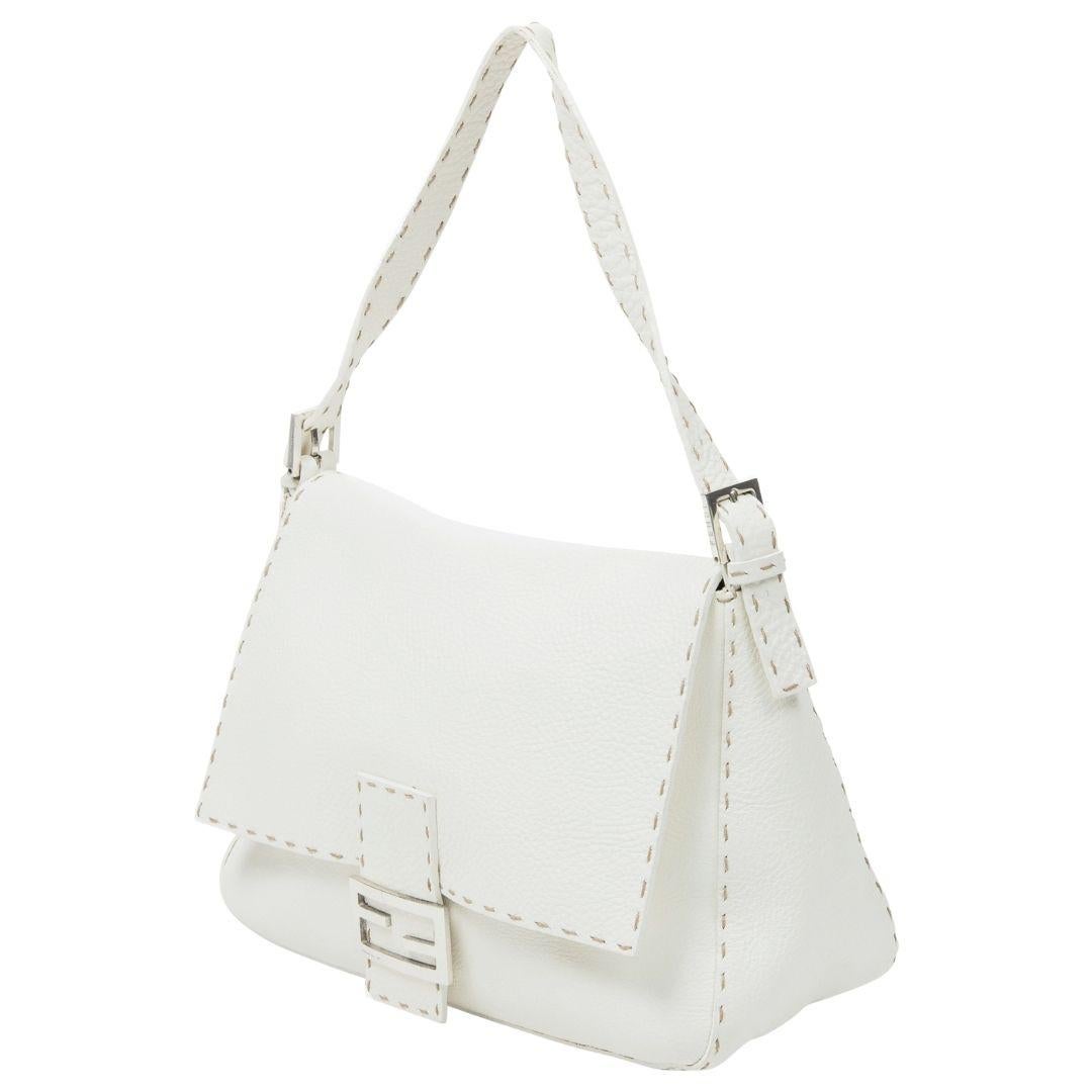 The white Selleria leather Fendi Mama Baguette is a statement of pure elegance. Silver-tone hardware and a magnetic snap closure meet a suede interior with a zippered pocket.

SPECIFICS
Length: 11.8
Width: 5.1
Height: 8.3
Handle drop: N/A
Strap