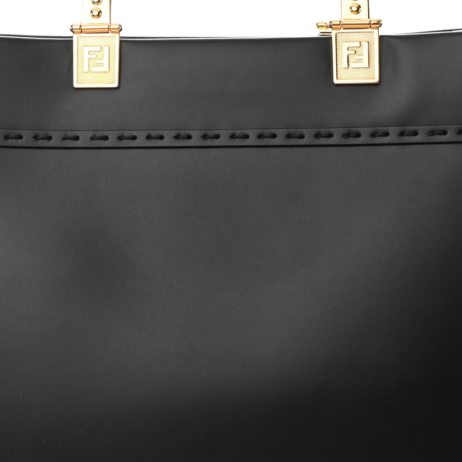 This is an authentic FENDI X VERSACE Calfskin Plexiglass Fendace Medium Fendi Sunshine Shopper Tote in Black. This stylish shopping tote is crafted of black leather, bold decorative gold print, stitched detailing, and logo patches. It features black