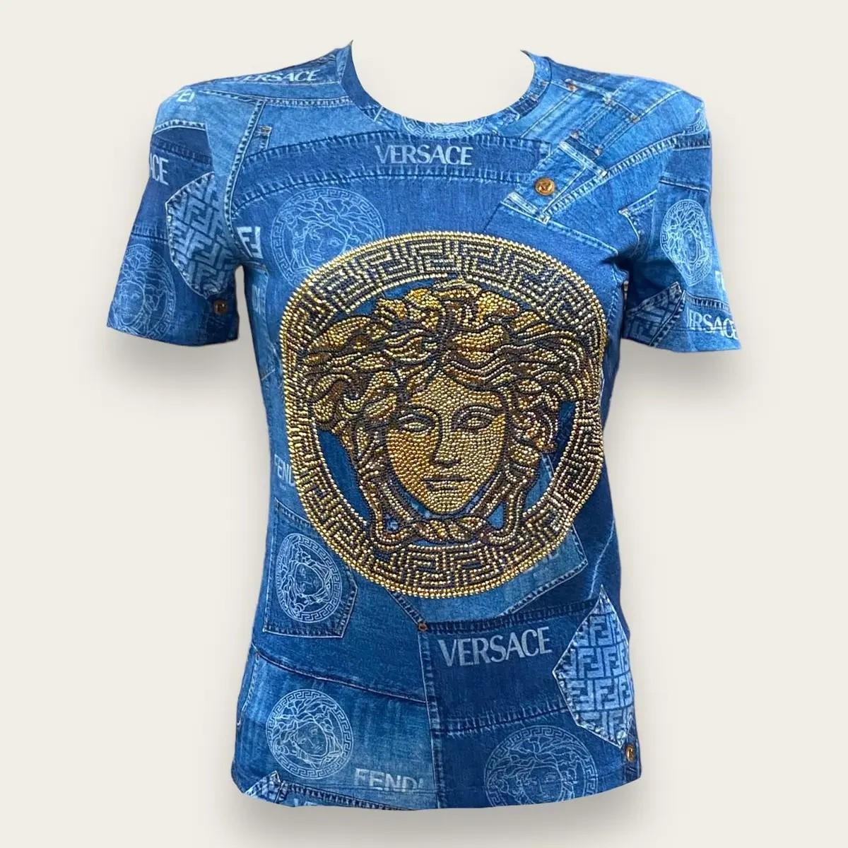 Esta camiseta de edición limitada, una pieza destacada de la exclusiva colección cápsula Fendace, encarna la fusión de la elegancia romana de Fendi y el glamour atrevido de Versace. Confeccionado en suave tejido de punto, presenta un llamativo