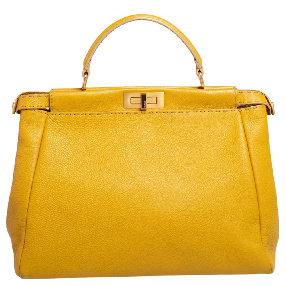 Exquisitely designed and highly coveted, this Peekaboo bag crafted by Fendi continues to sway everyone with its structure, design, and skilled craftsmanship. Made with yellow Selleria leather and gold-toned implements, this bag lets you explore a