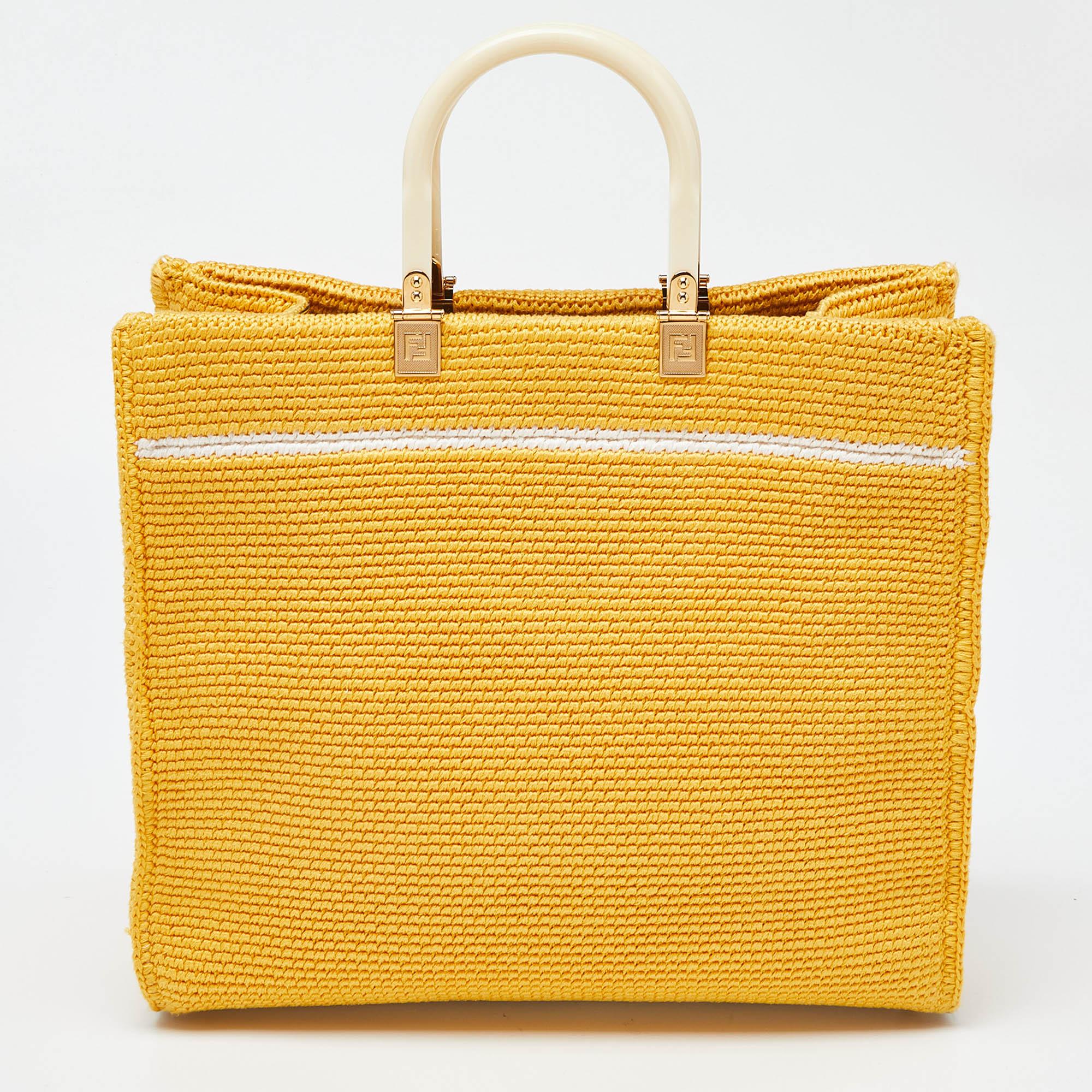 The Fendi Sunshine Tote is a luxurious and versatile handbag. Crafted from supple crochet and leather, it features a spacious interior. The iconic Fendi logo is on the front, and the bag is adorned with elegant gold-tone hardware. A detachable