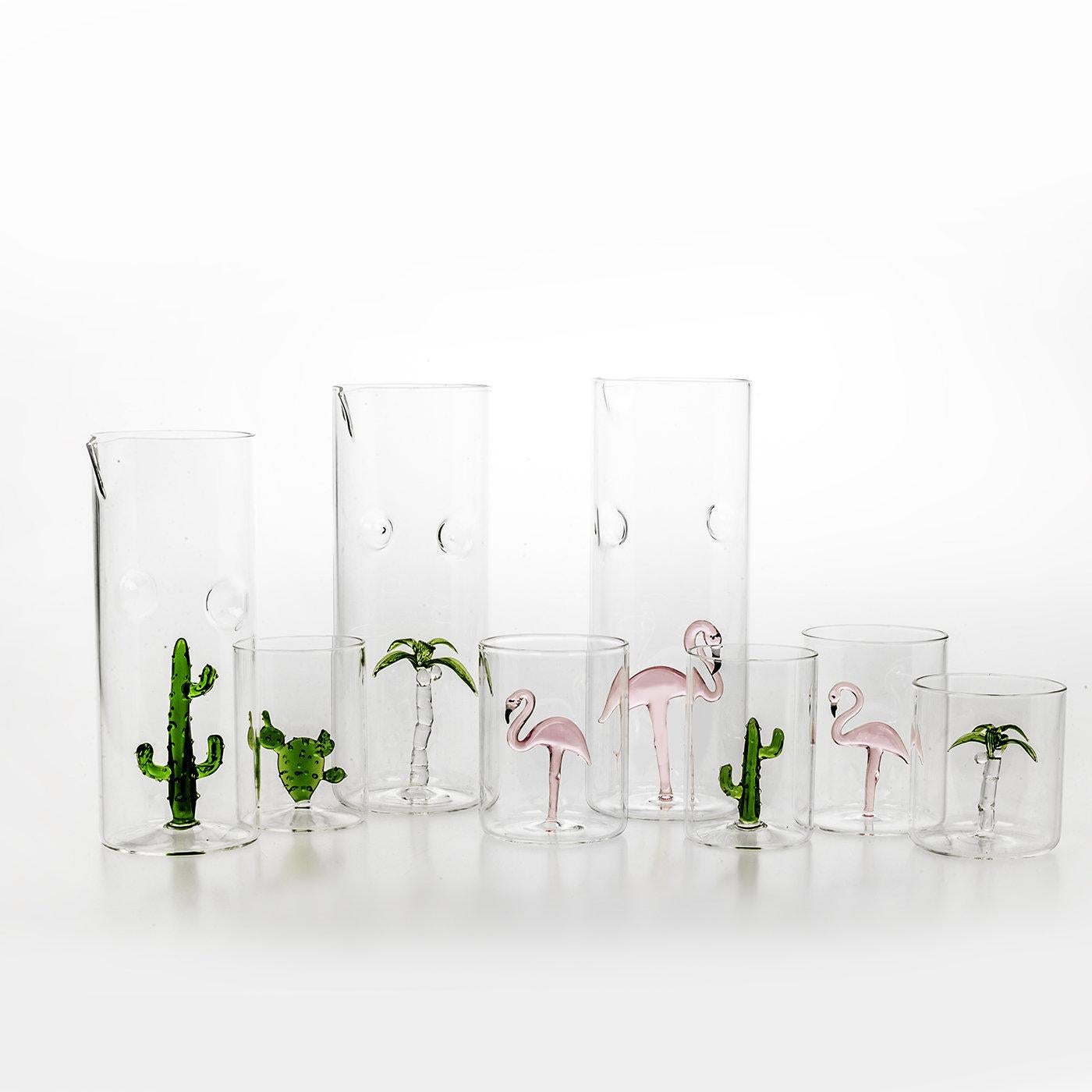 Exquisitely handcrafted and versatile, this charming set comprises one pitcher and four glasses adorned with the image of a flamingo, hand-painted in pink with black and white details. The birds are sculptural elements blown into the pieces and