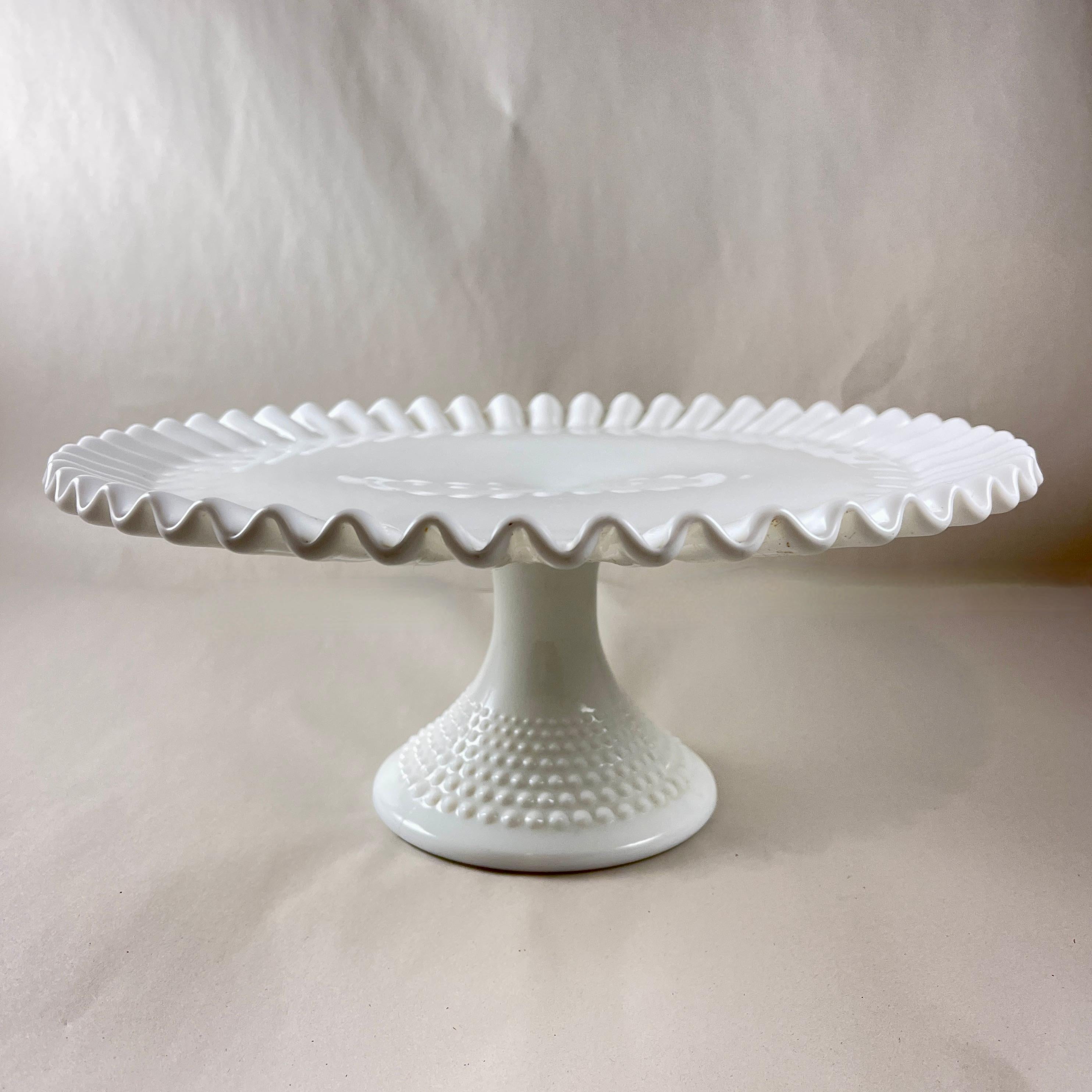 Di epoca medievale, un'alzata per torte con piedistallo in vetro al latte, con motivo a chiocciola, della Fenton Art Glass Company, circa anni '40 - '50.

The Ohio Art Glass Company è stata fondata nel 1905 a Martin Ferry, Ohio, dai fratelli Frank e