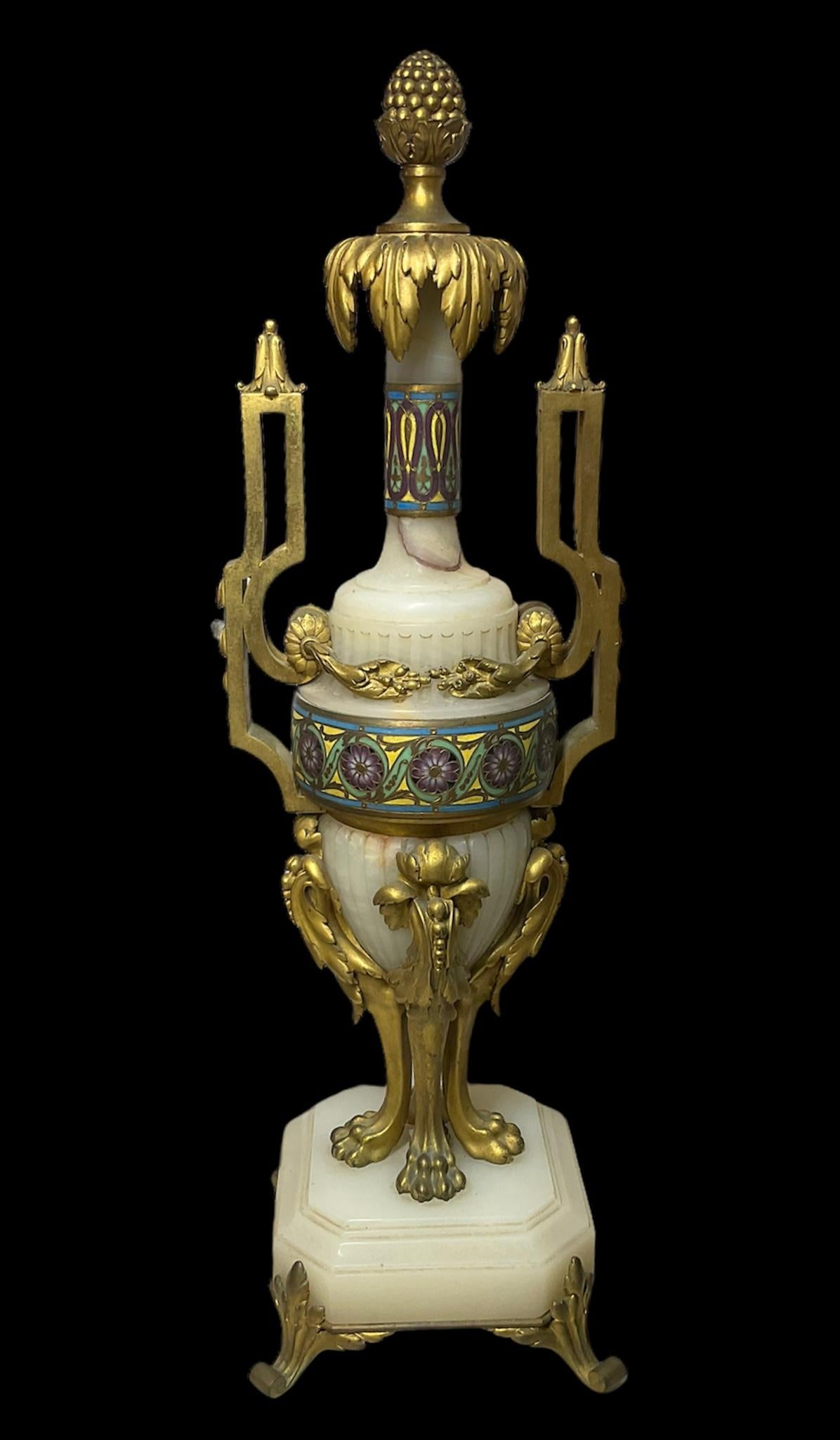 This is a Ferdinand Barbedienne set of gilt bronze-mounted champleve onyx garniture. It consist of two urns and one large oval vase/jardiniere. The vase is adorned with a chain of gilt beads in its rim and from its gilt bronze scroll-rectangular
