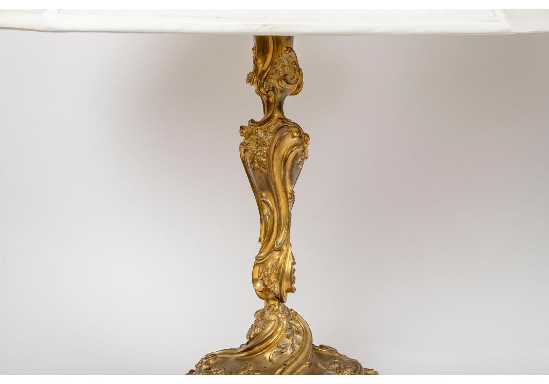 An impressive and rare pair of antique dore bronze candlesticks mounted as lamps. The candlesticks with beautifully cast scrolls, florals, shells and foliate motifs in the rococo style. Mounted with enamel finished standards with dual sockets with