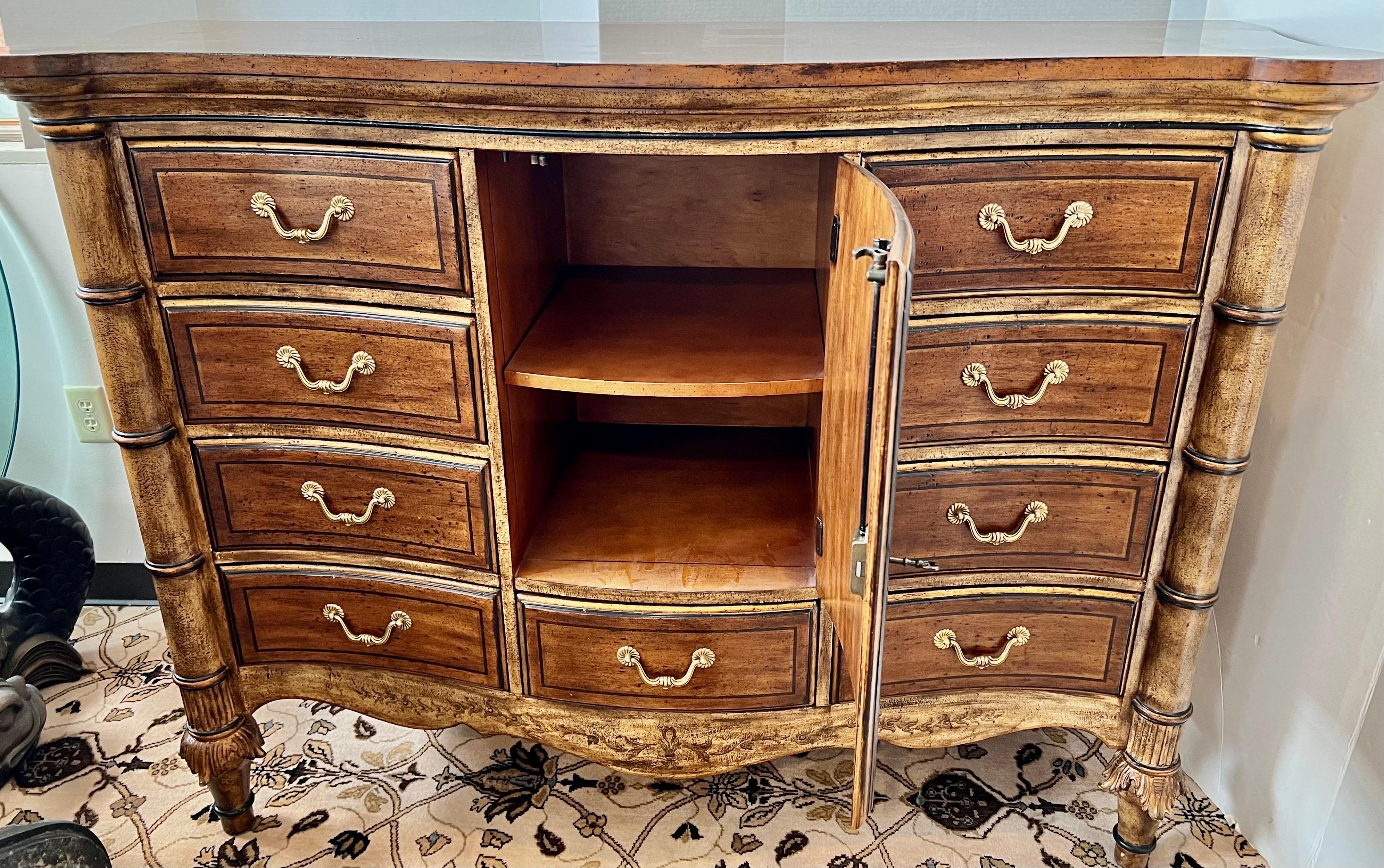 Elegant multi-purpose Ferguson Copeland Venetian dresser or sideboard by Ferguson Copeland. It has a bowed front between cylindrical legs with ring accents ending on carved feet. It has a center door with painted gold and black scrolled border,
