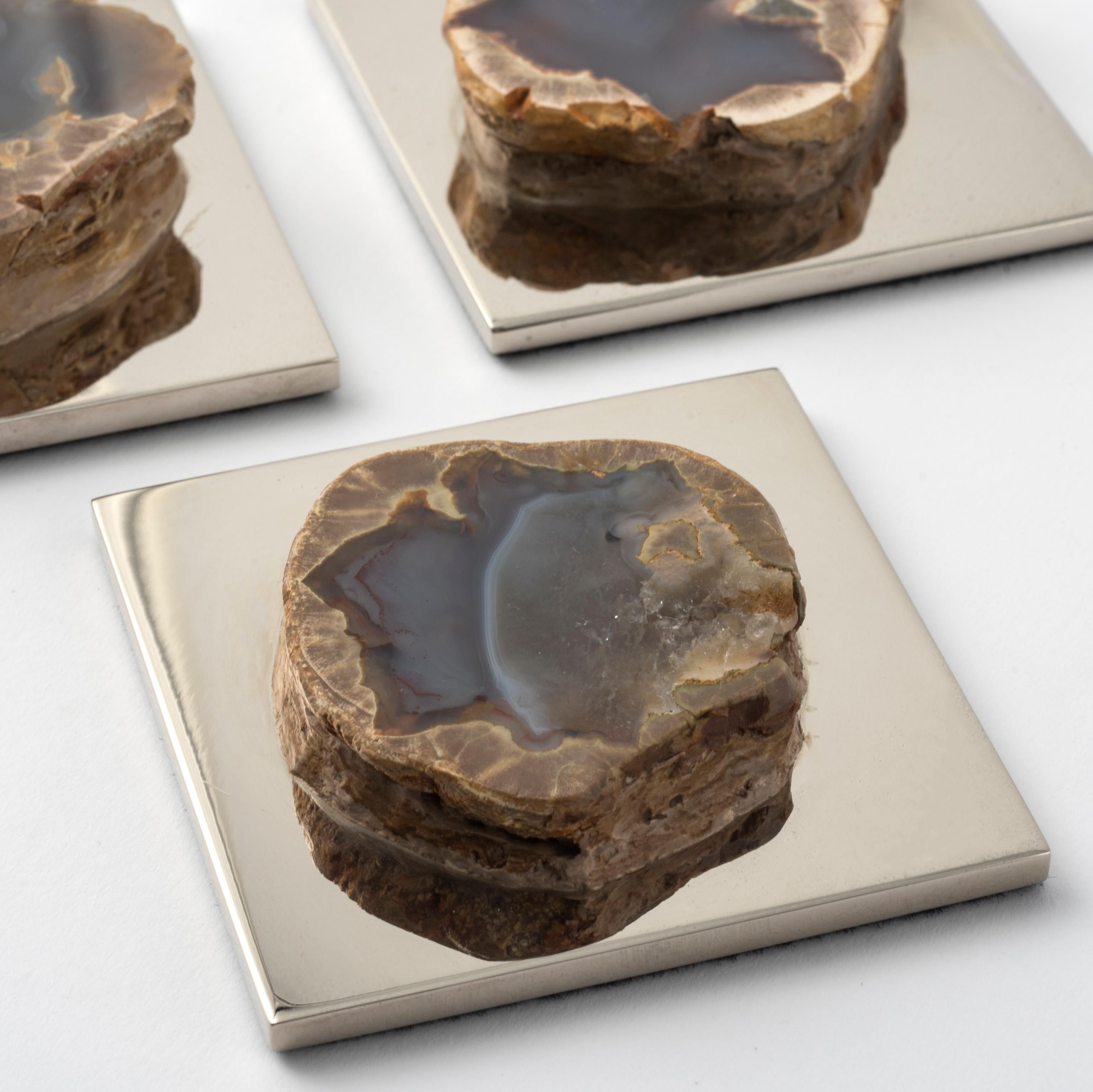 Un petit objet de grand charme : ce presse-papier au design contemporain allie l'éclat du laiton nickelé à la beauté brute et authentique d'une géode d'agate naturelle. 
Les teintes bleutées de la pierre minérale varient d'un spécimen à l'autre 
