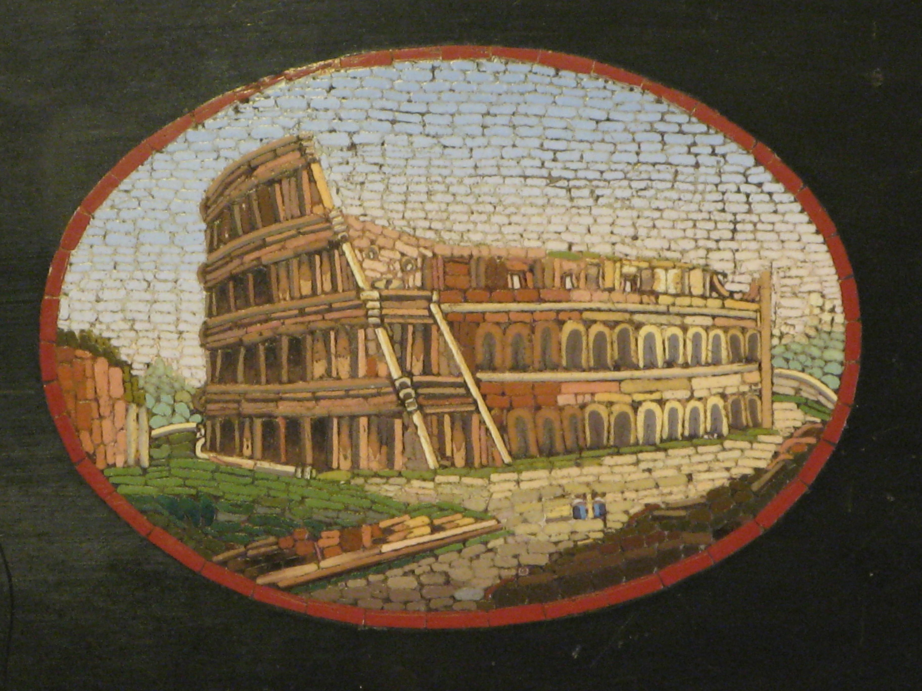 Elegant Belgian black marble paperweight shaped at the edges with central oval plaque containing a micro-mosaic depicting a view of the Colosseum (Rome). 
These examples of micromosaics with views and glimpses of cities were typical souvenirs of the