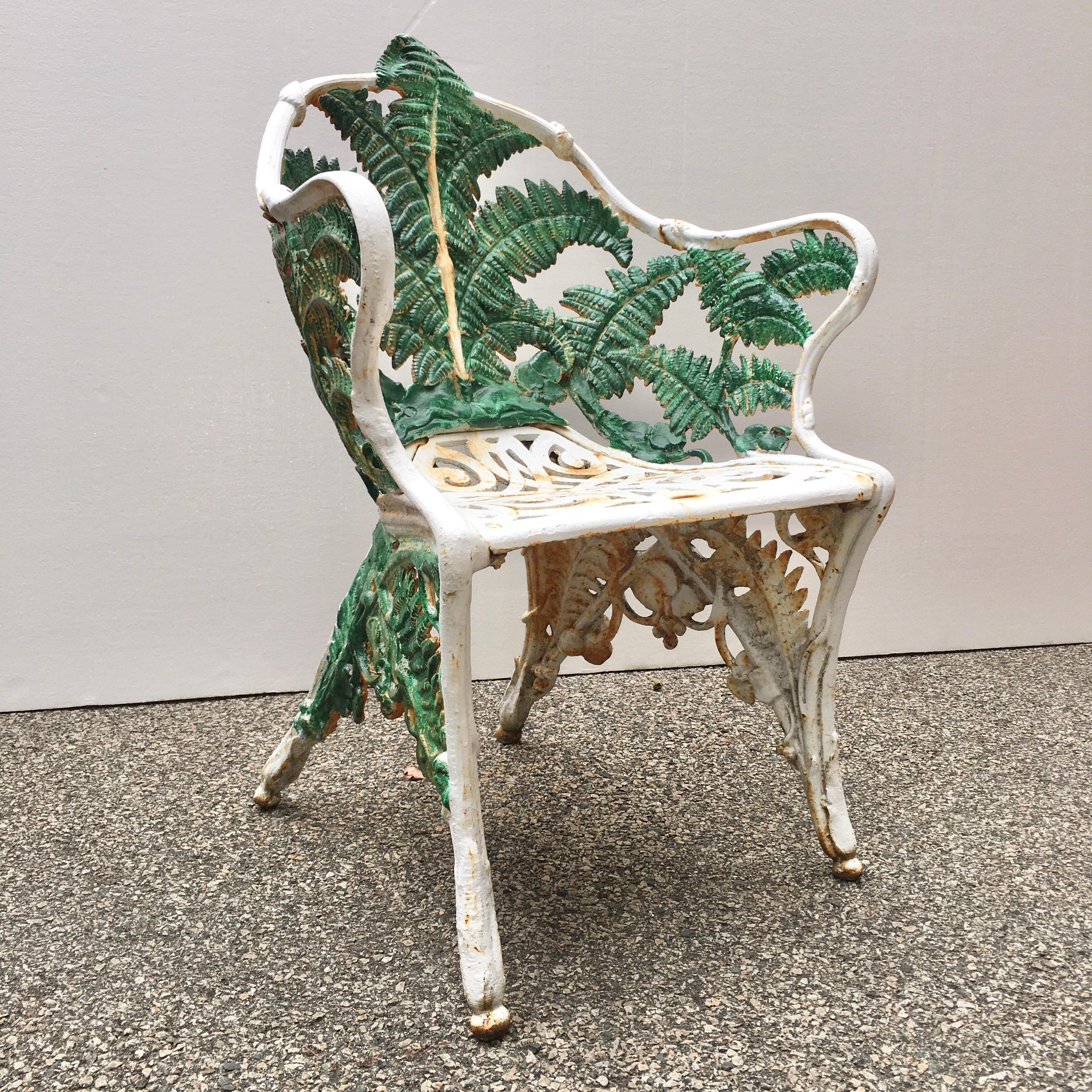 Cast iron Fern and Blackberry pattern garden chair with shaped pierced scroll work seat and older repaint in white and green.
The chair features well-defined foliage pattern on the interior back and arms of the bench with foliage cast on both inner