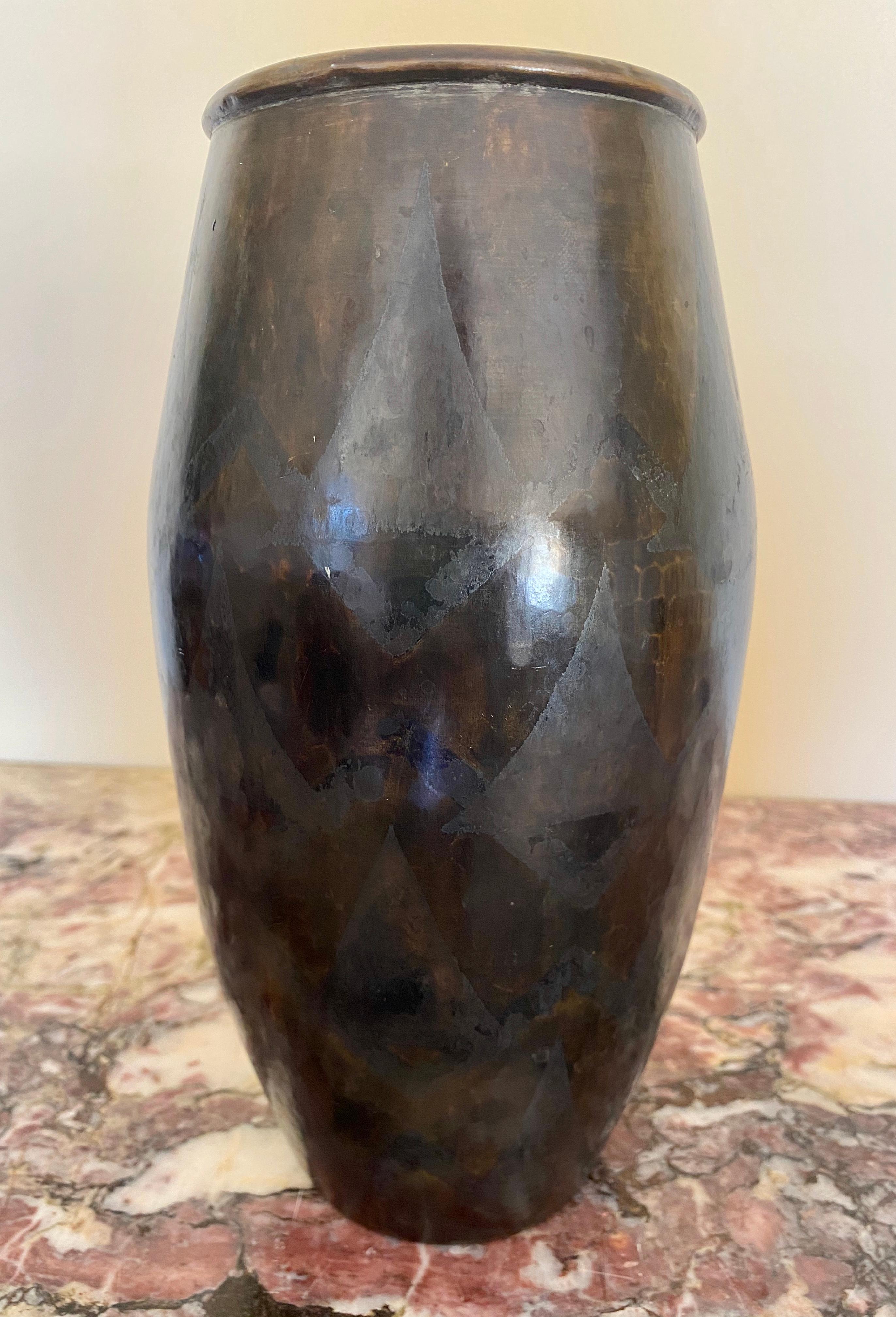 Grand vase ovoïde allongé en laiton entièrement martelé. Décor de triangles superposés, argent et bronze oxydés sur un fond à patine brune nuancée. Circa 1930/1935.
Signé en bas 