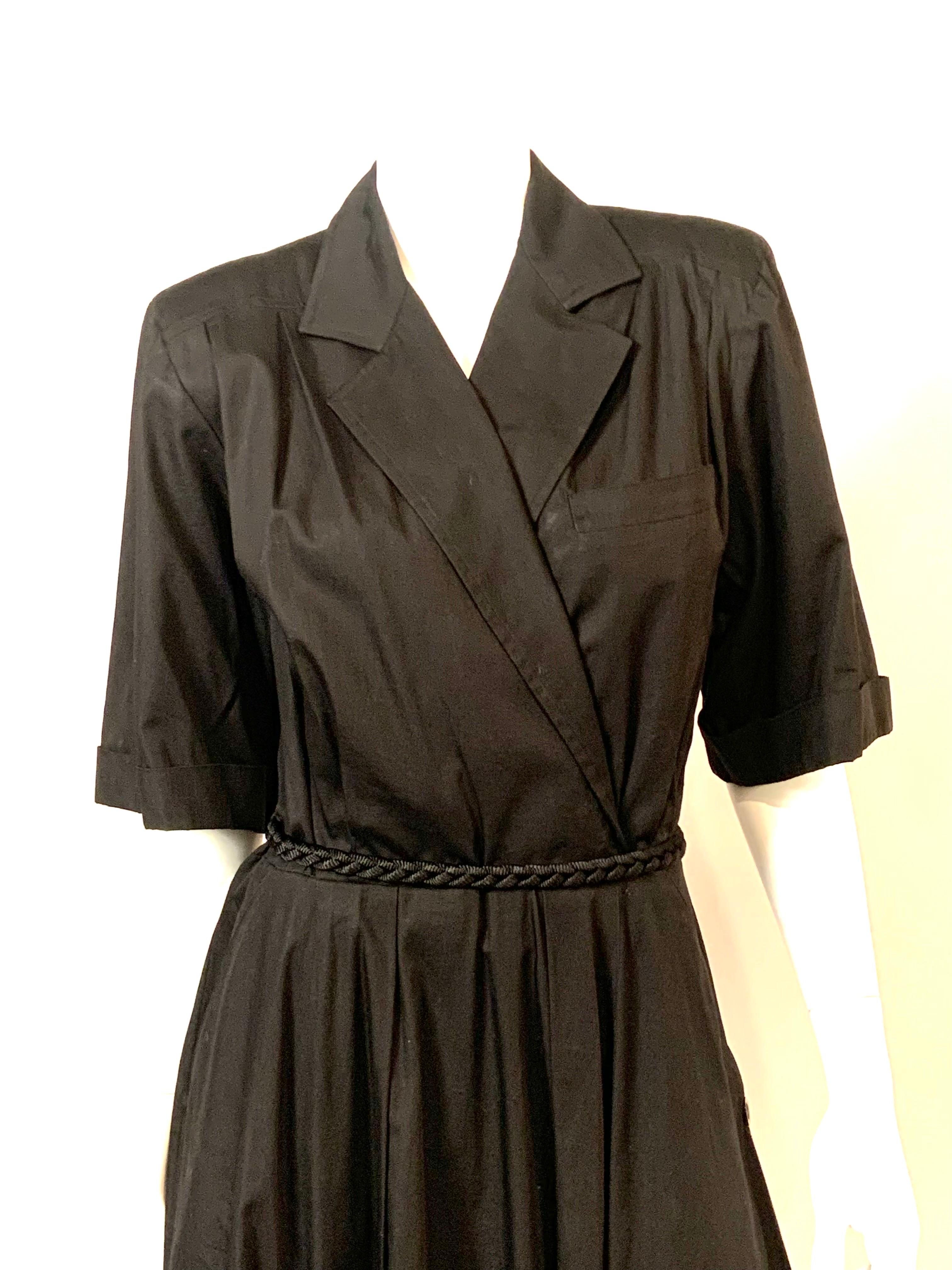 This black cotton dress from Ferragamo has a notched collar, left side breast pocket, short sleeves and a faux wrap style.  There is a left side zipper, a full skirt with two hip pockets and buttons on the left side from the hip pockets to the hem.