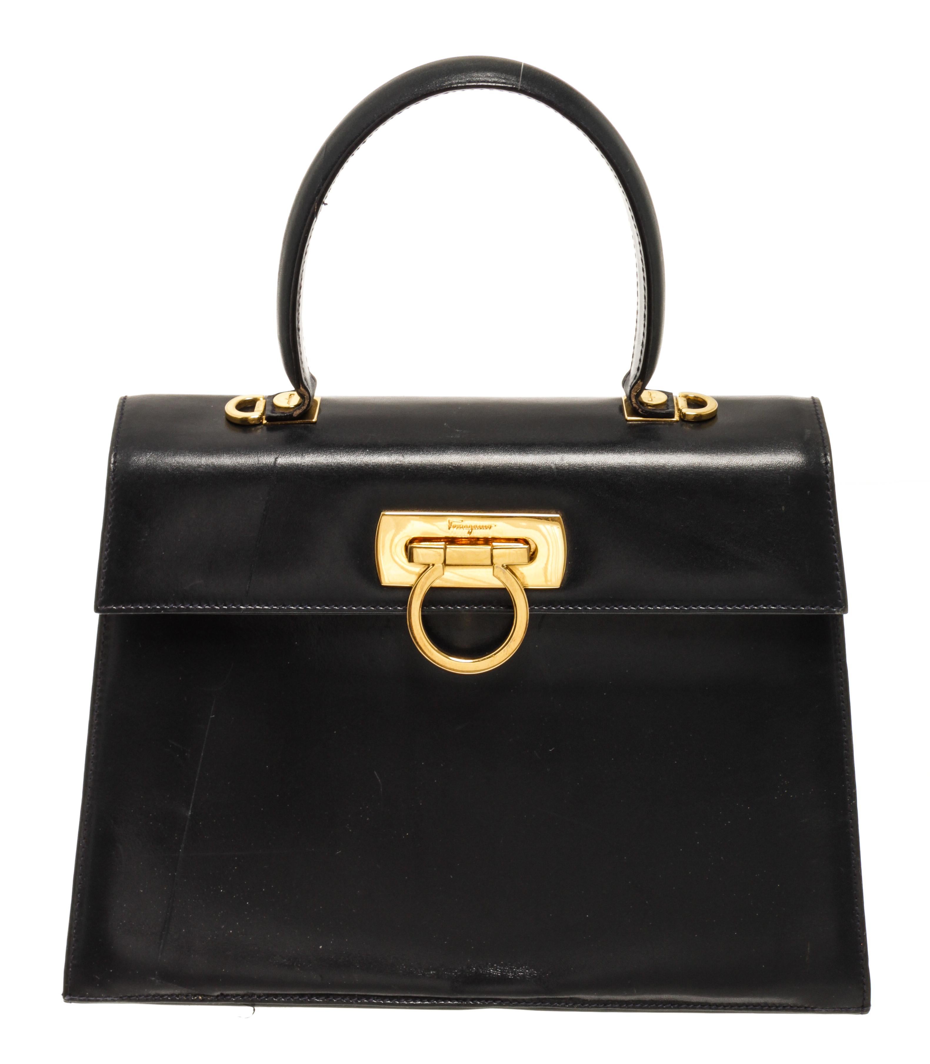 Ferragamo Black Ganci Shoulder Bag with a top handle, adjustable straps, gold tone hardware, one interior zip pocket and turn lock closure.

440237MSC