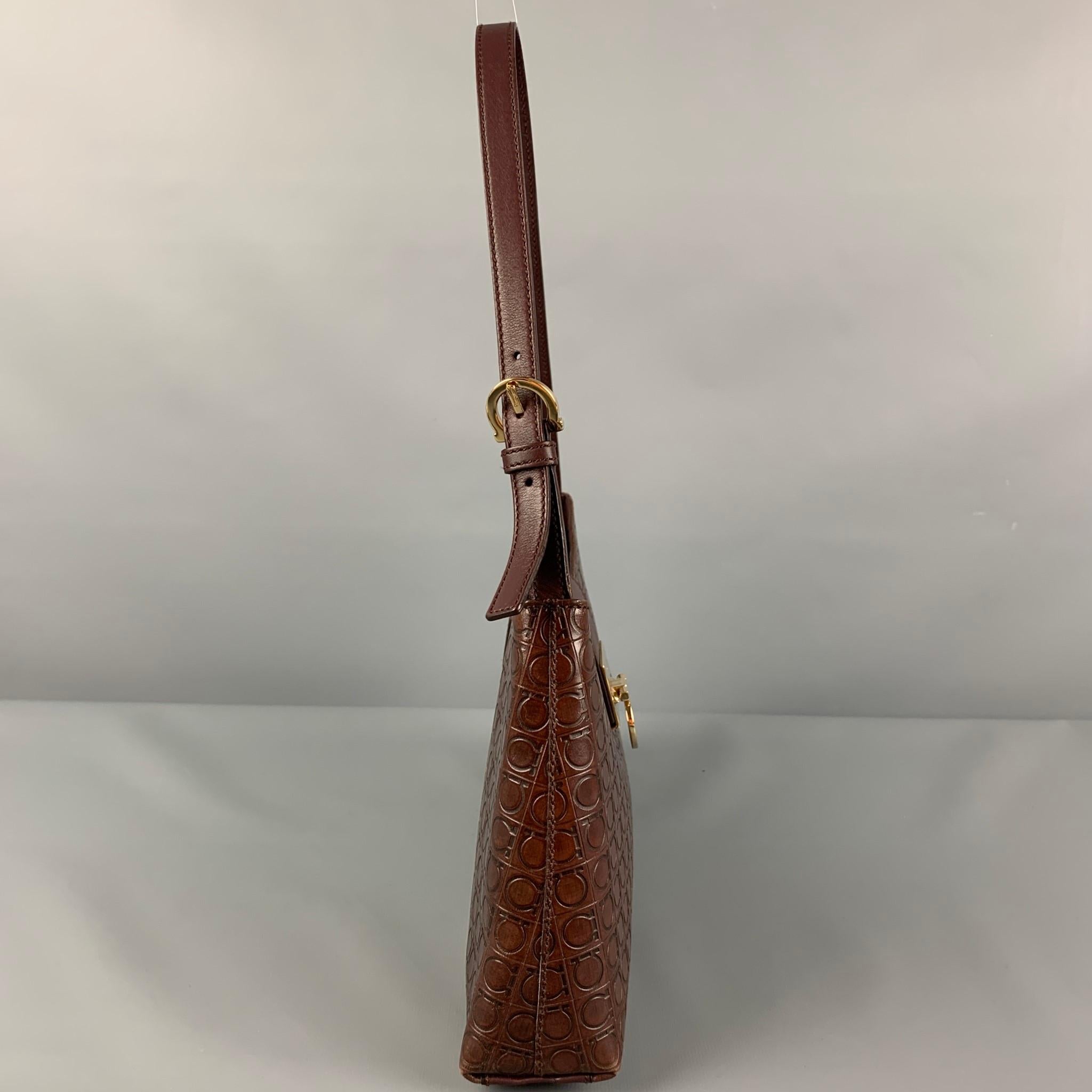 FERRAGAMO handbag comes in a brown embossed leather featuring a shoulder strap, gold tone hardware, and a turn lock closure. Includes authenticity cards. Made in Italy. 

Very Good Pre-Owned Condition.
Marked: D 21 2750

Measurements:

Length: 12.25