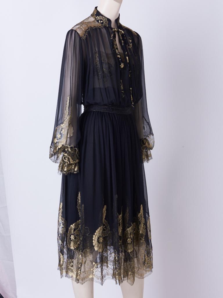 Ferragamo black silk, georgette peasant style dress with a chiffon under pinning. Dress has gossamer gold  lace detail at cuffs, sleeves, shoulders, and hem. Mandarin style collar, with tie.
