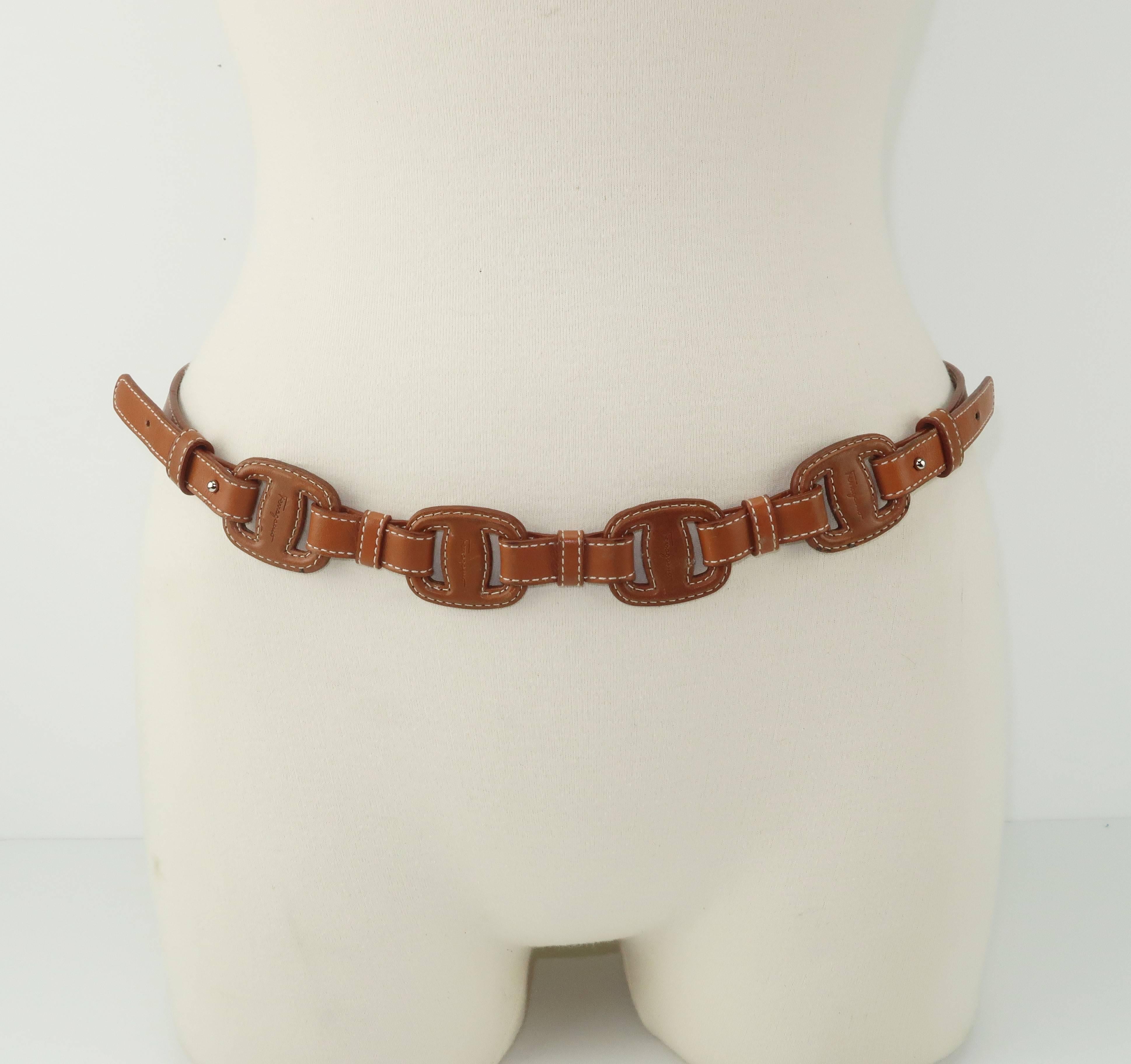 Ferragamo creates a skinny tan leather belt with the look of a bridle lending it an equestrian vibe.  The versatile tan leather is designed with two adjustable sides providing for three options on each end.  The Ferragamo name is embossed on both