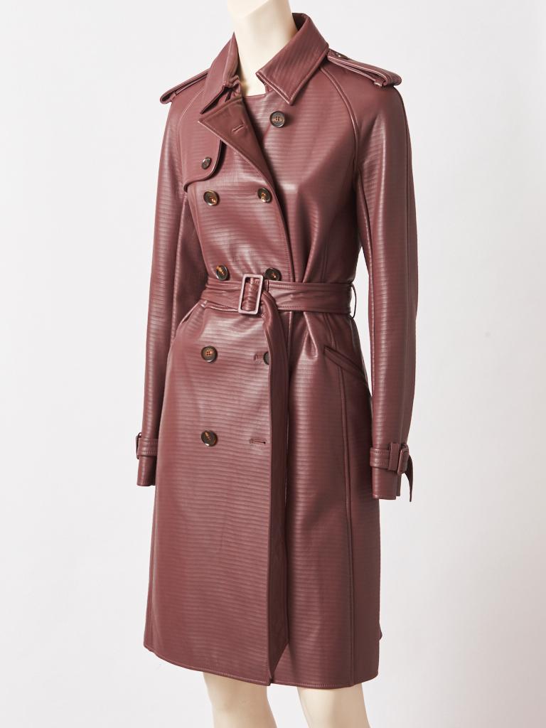 Ferragamo, chocolate brown, classic style, double breasted, leather trench, having epaulettes, and an embossed horizontal, stripe detail, giving texture to the coat.