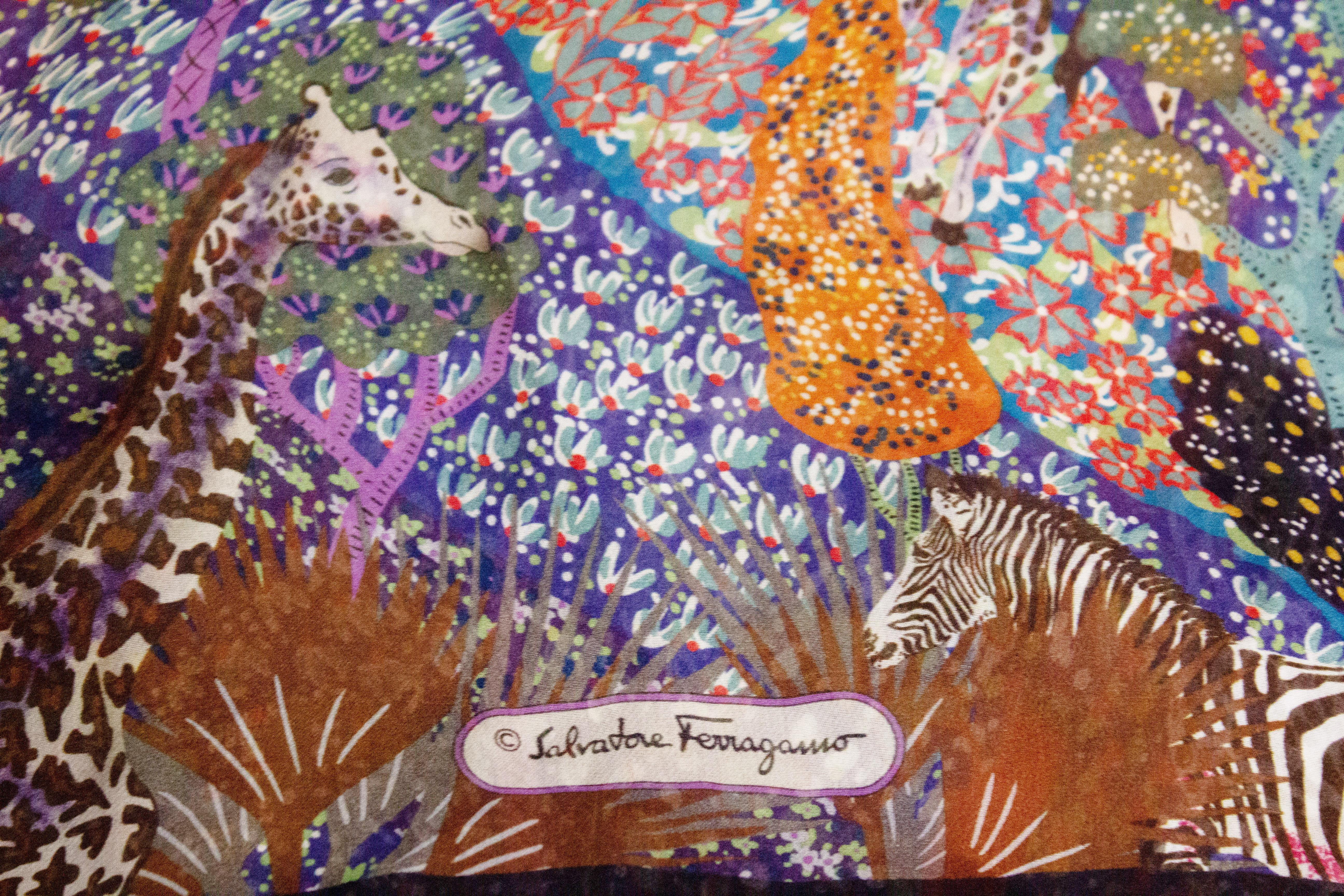 A pretty silk chiffon scarf by Ferragamo. The scarf has a black background with a multicolour animal print and has hand rolled edges. Measurements: width 17' , length 64''.