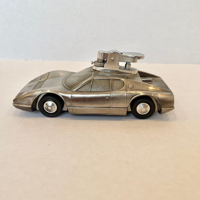 Cool 1980s table lighter in the shape of a Ferrari 365 GT4 BB. 'Made In Japan' sticker on the underside. This vintage piece has great balance and details like rubber wheels that roll. Ferrari logo on the front while the back says 'Ferrari' on the