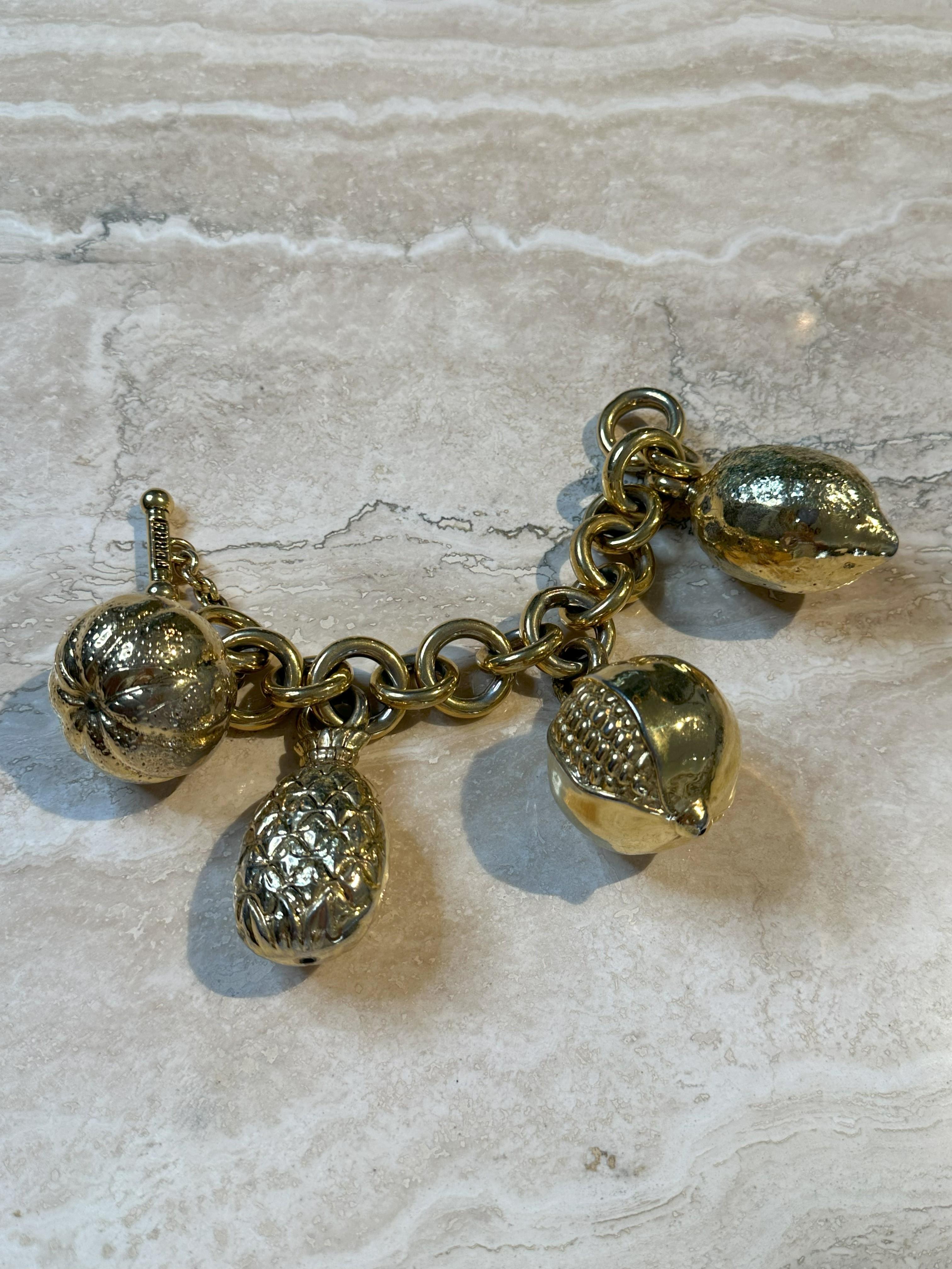 This impressive bracelet is in gold-tone metal with four very large fruit-shaped charms—pineapple, pomegranate, and lemon. Gianfranco Ferre was known as 